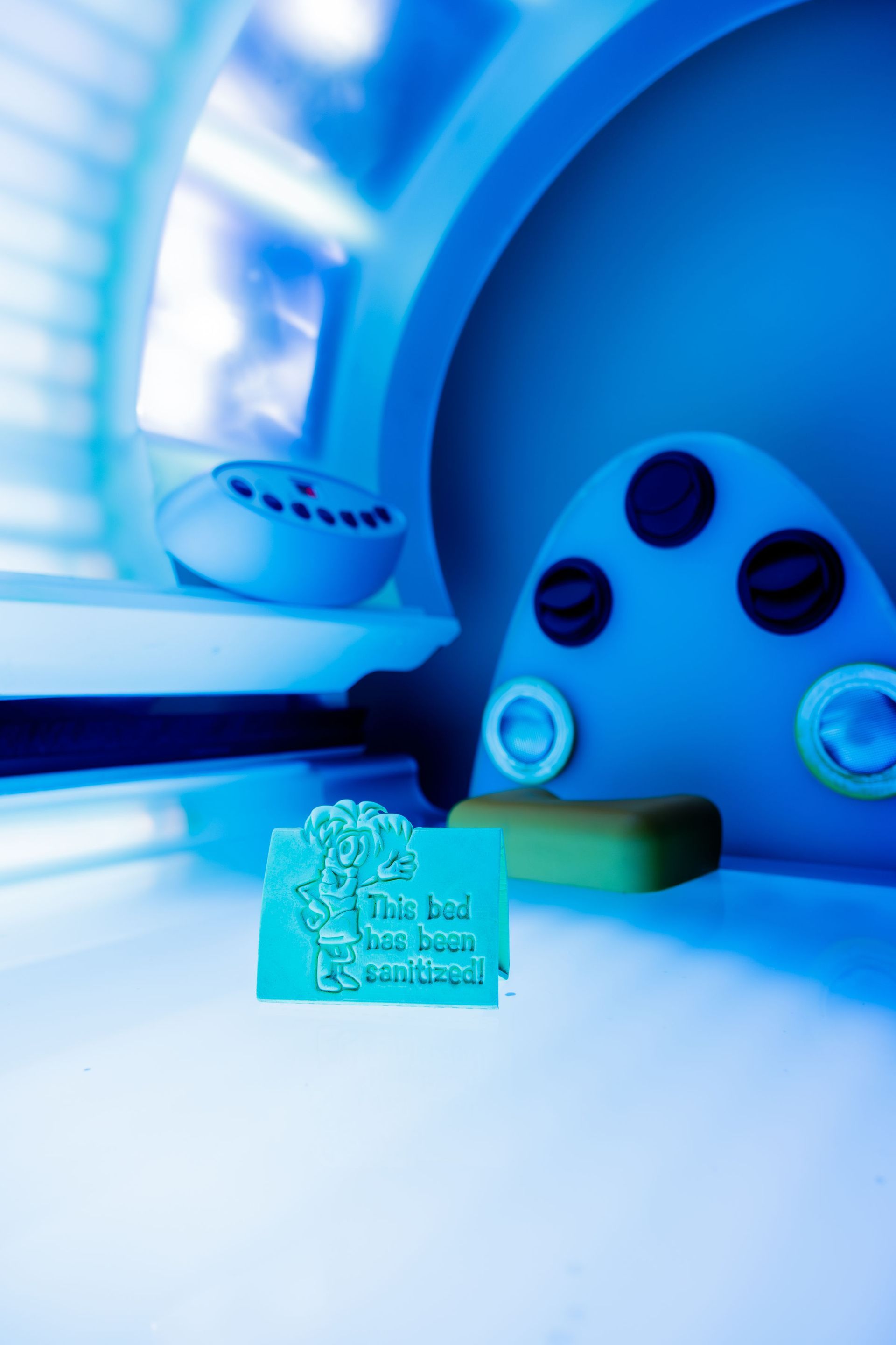 Interior of a tanning bed with controls and a sign in blue light.