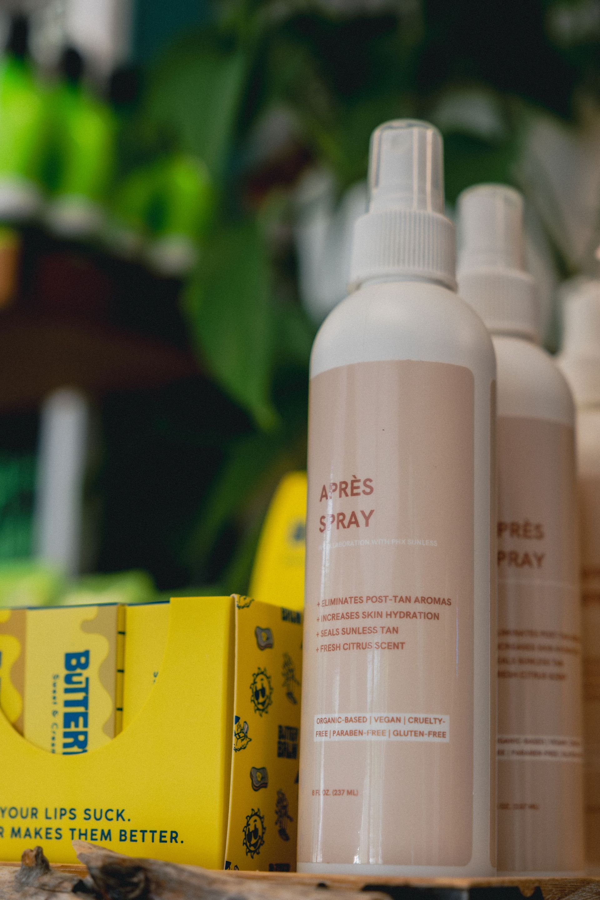 Two off-white spray bottles with pink labels, and a yellow box with 