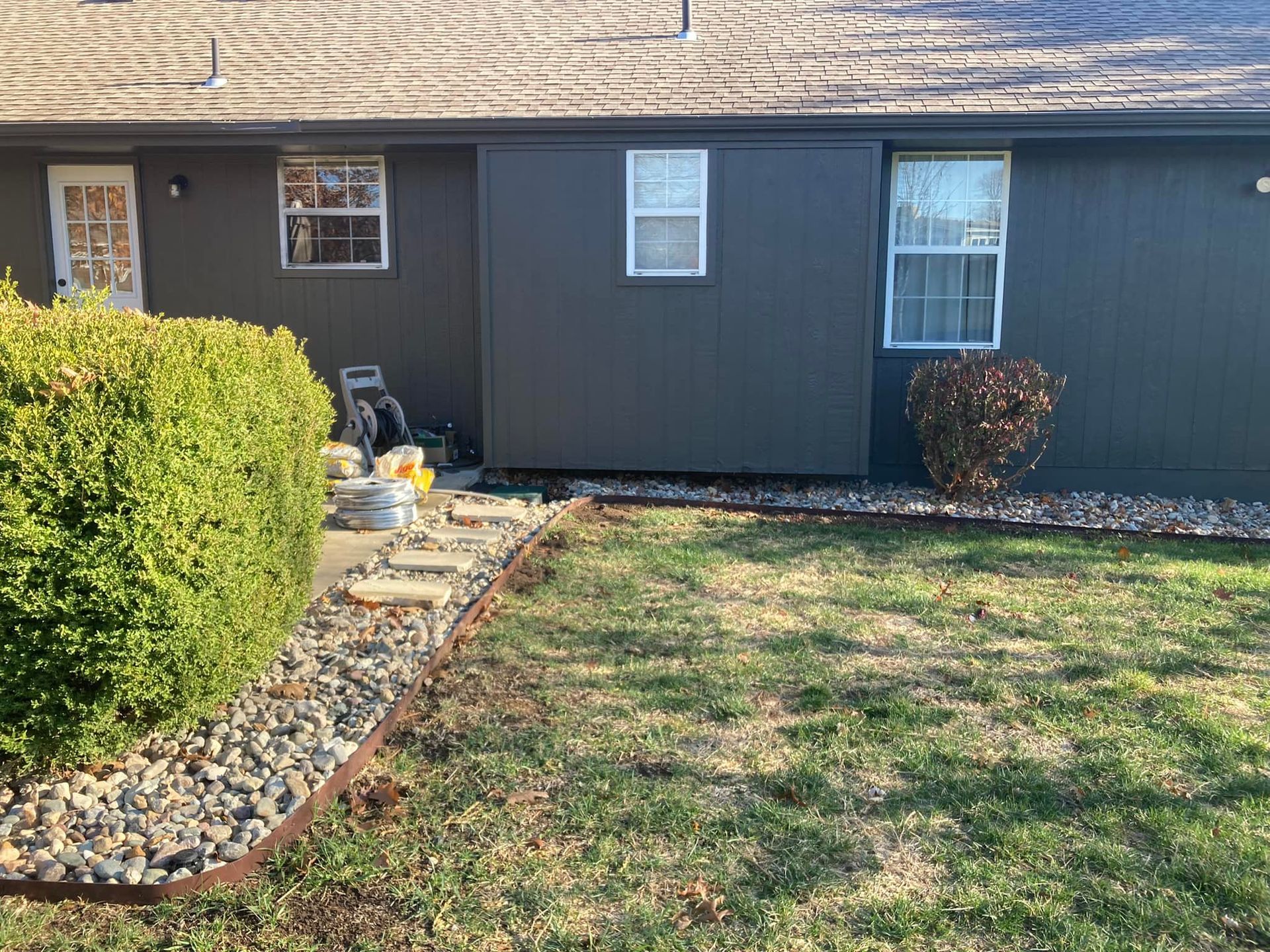 A house with a lot of grass and rocks in front of it.