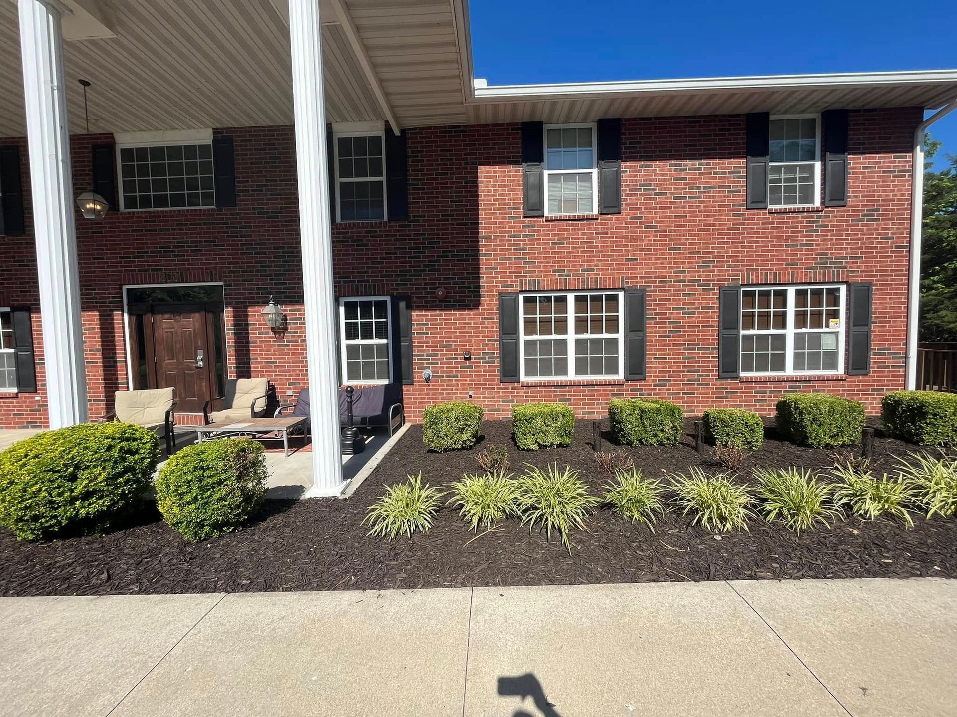 A large brick house with black shutters and a porch