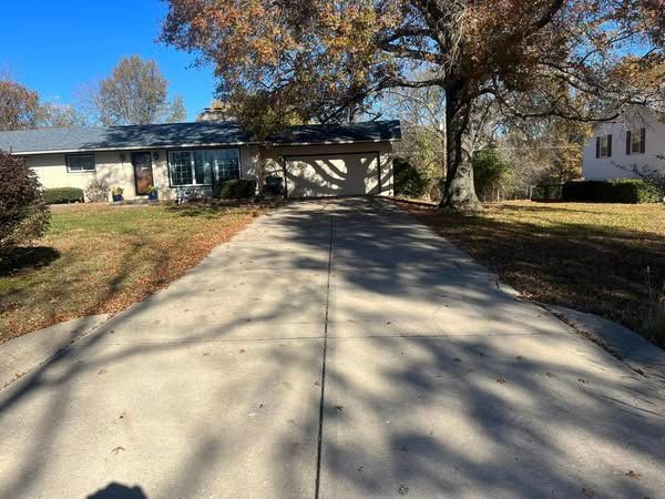 A concrete driveway leading to a house on a sunny day.