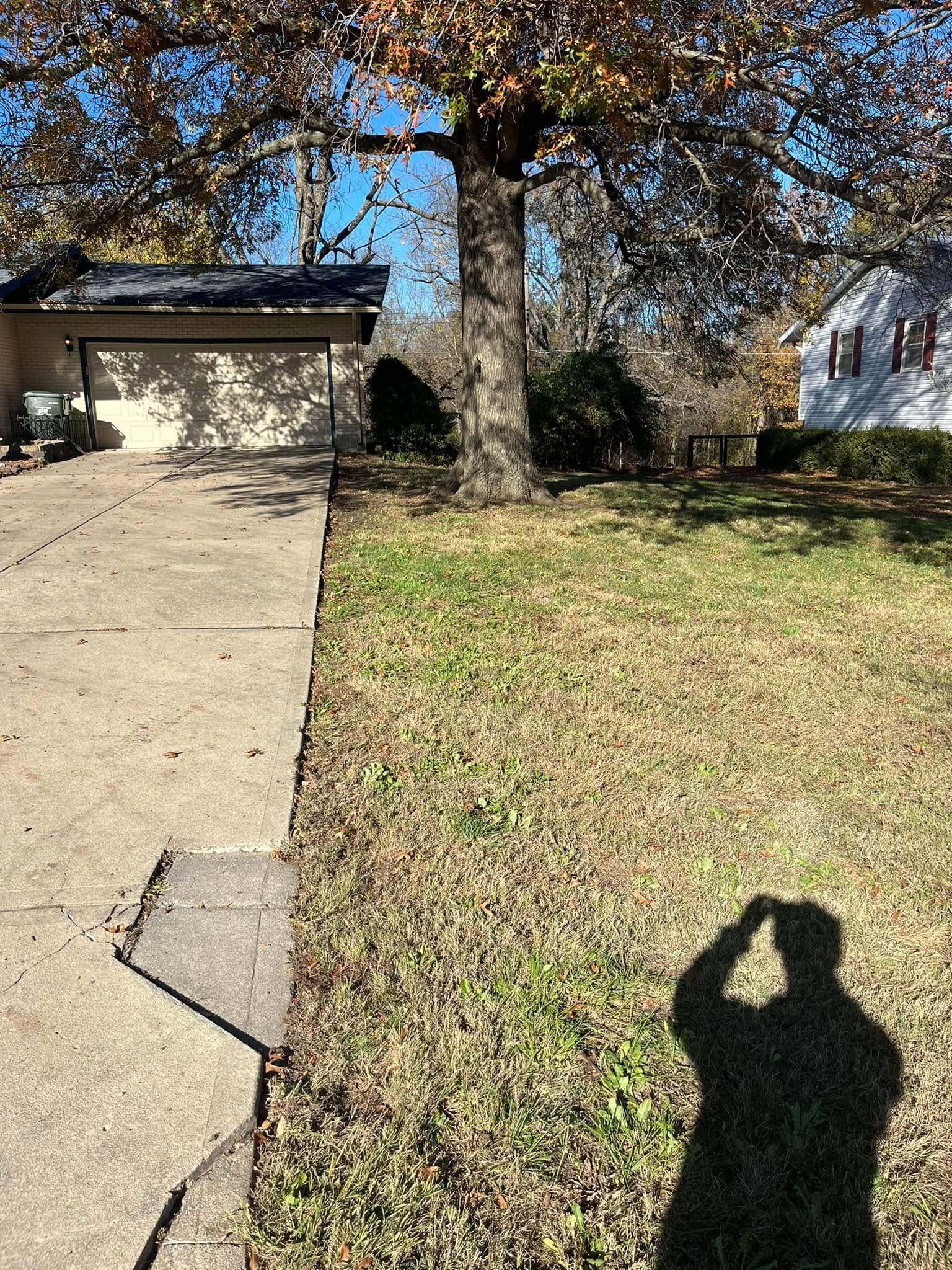 A person is taking a picture of their shadow in front of a house.