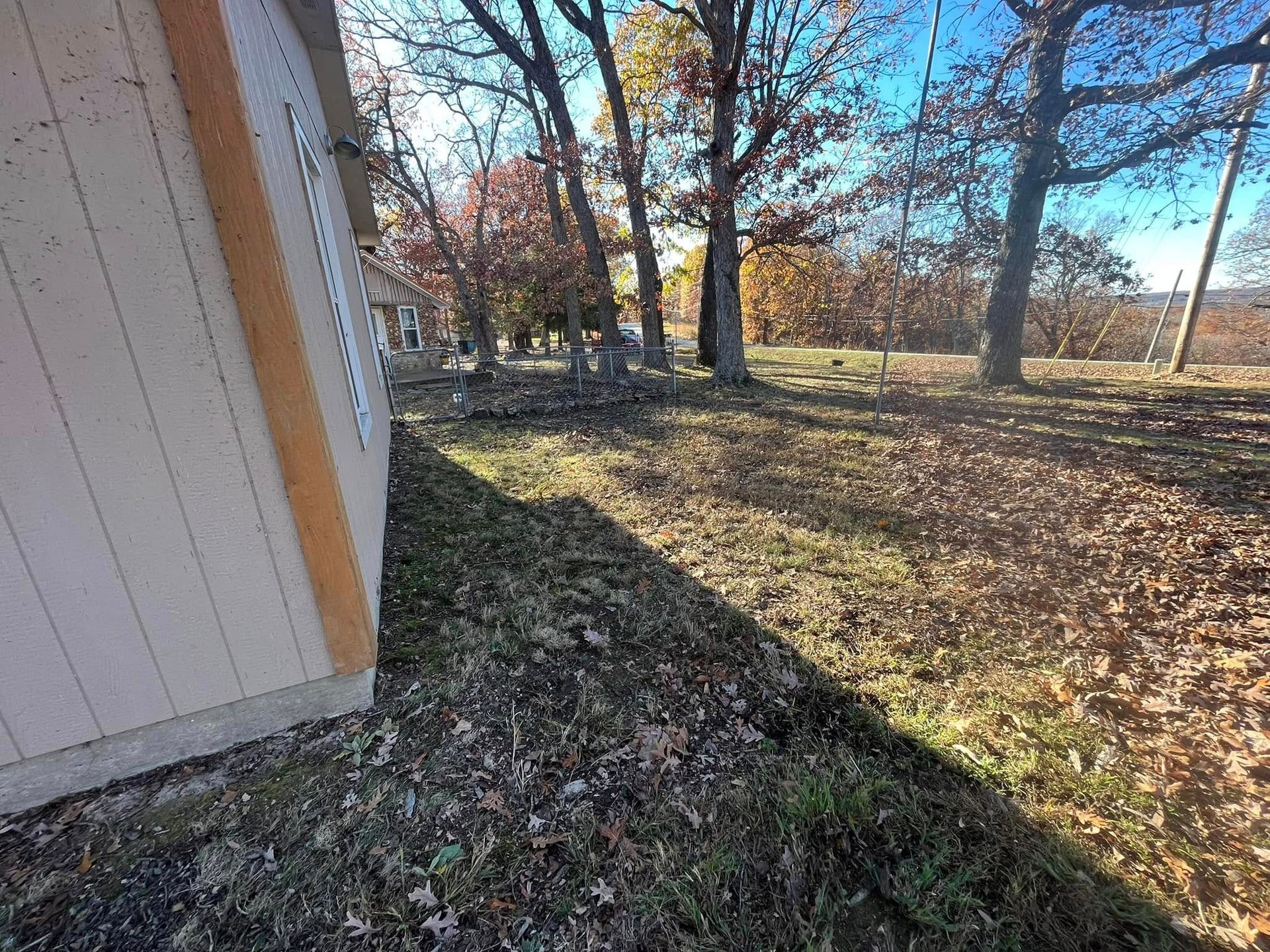 A shed is sitting in the middle of a field with trees in the background.