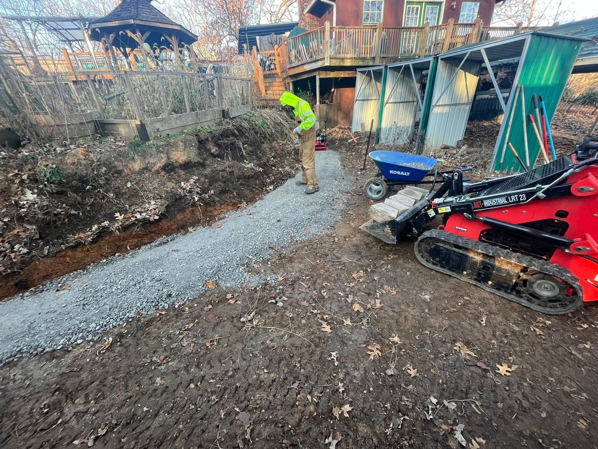 A man is standing next to a red tractor on a dirt road.