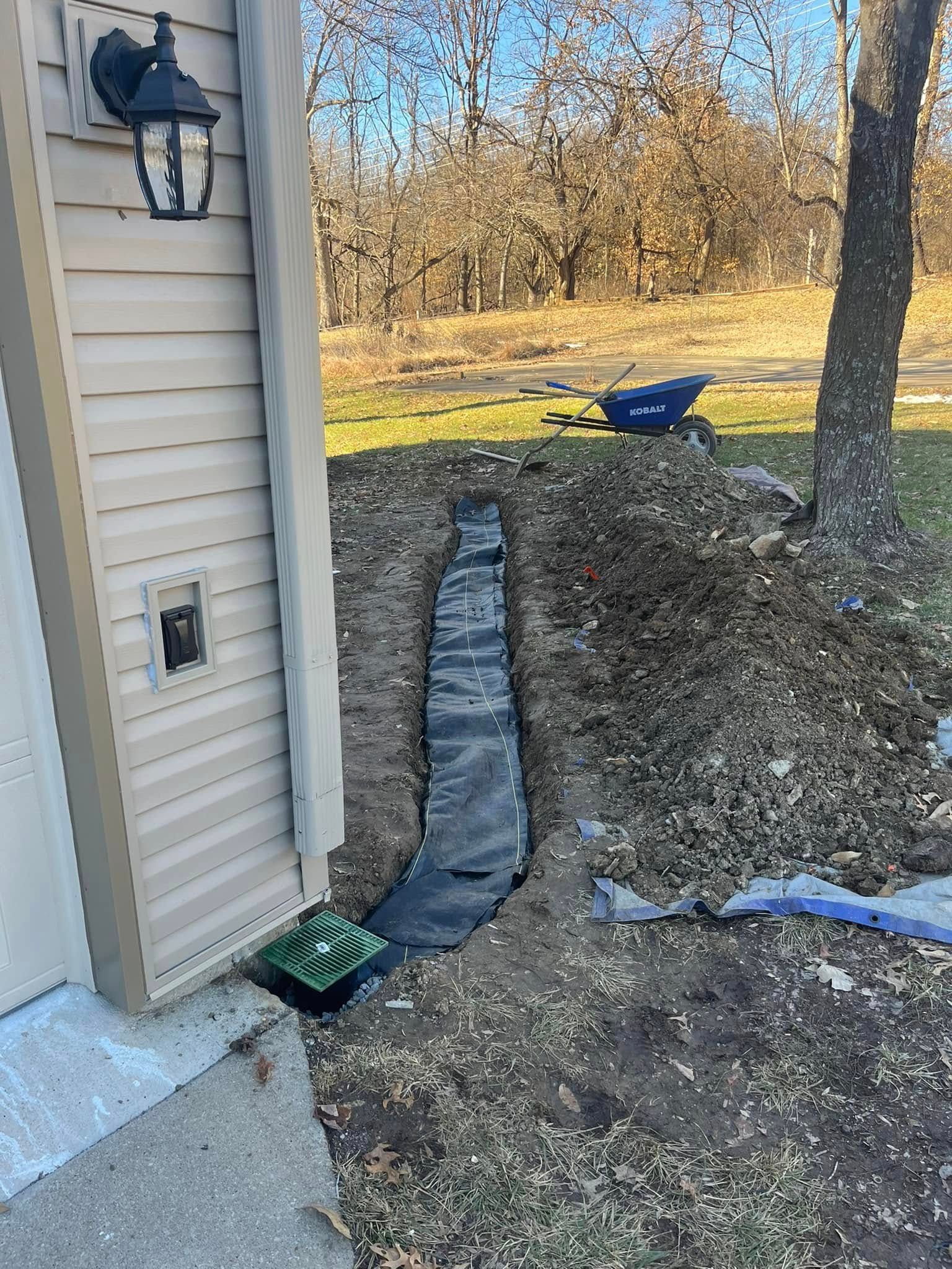 A drainage system is being installed on the side of a house.