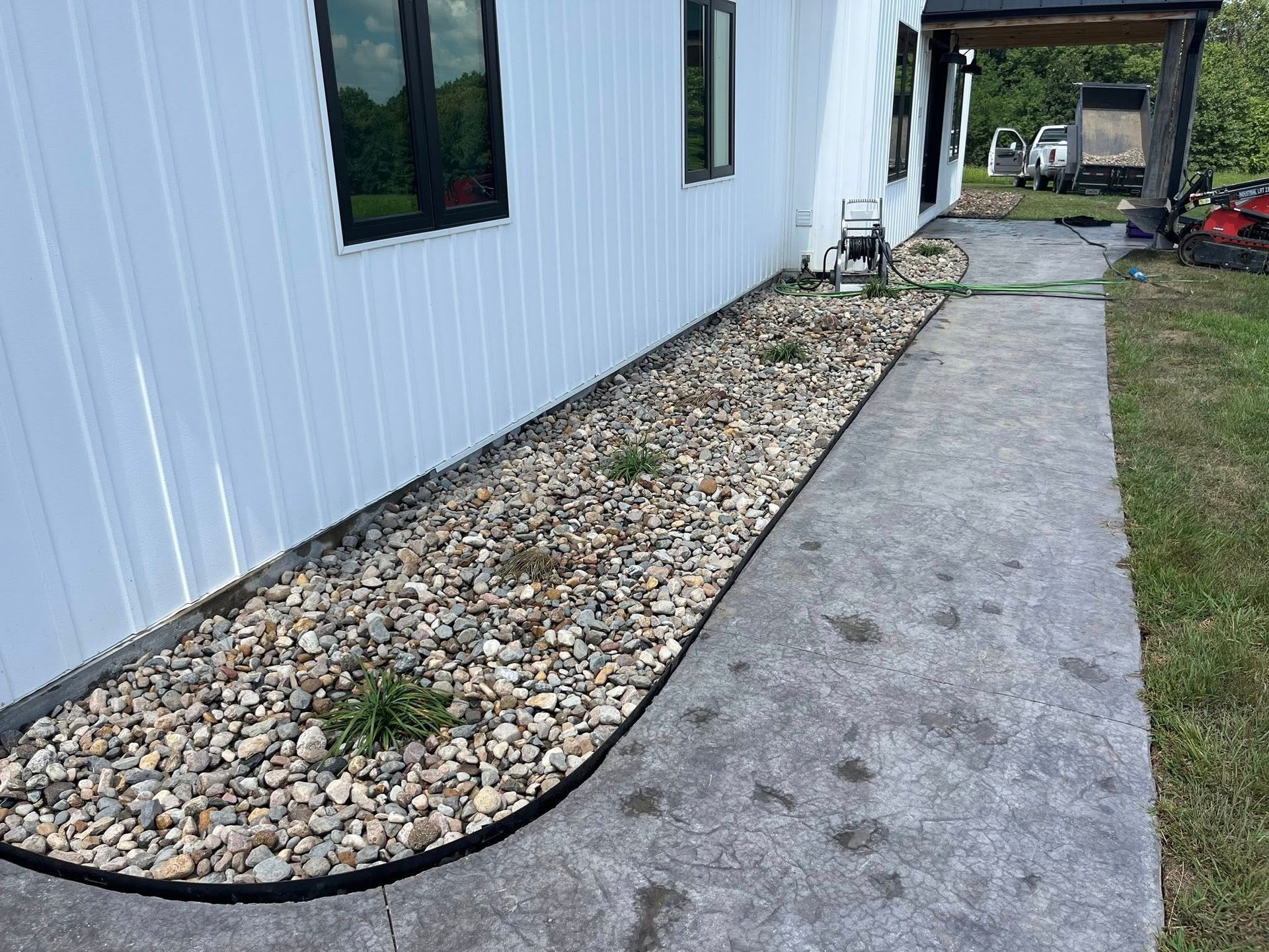 A lawn with rocks and a ladder in front of a house.