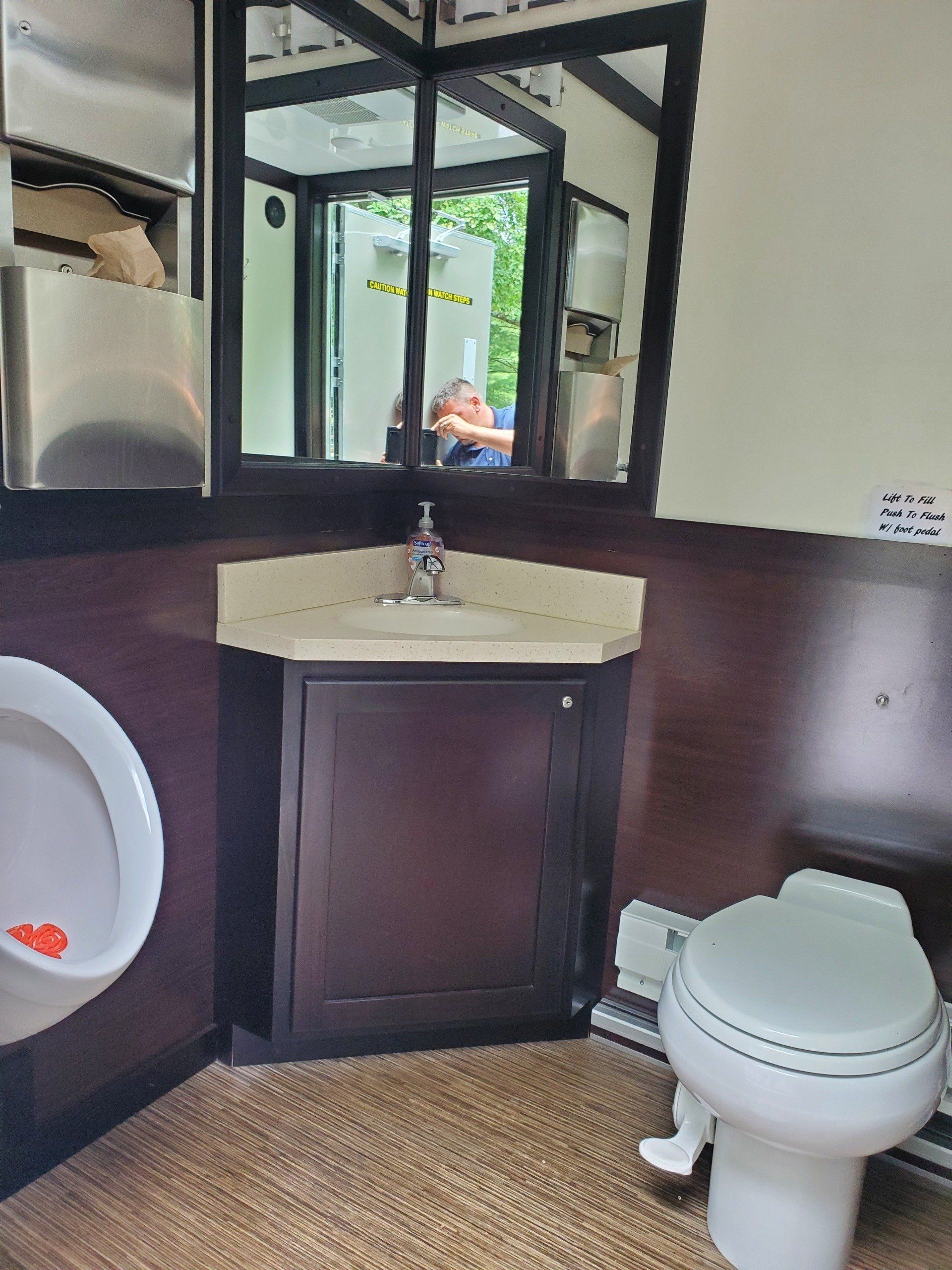 A bathroom with a toilet , sink and mirror.