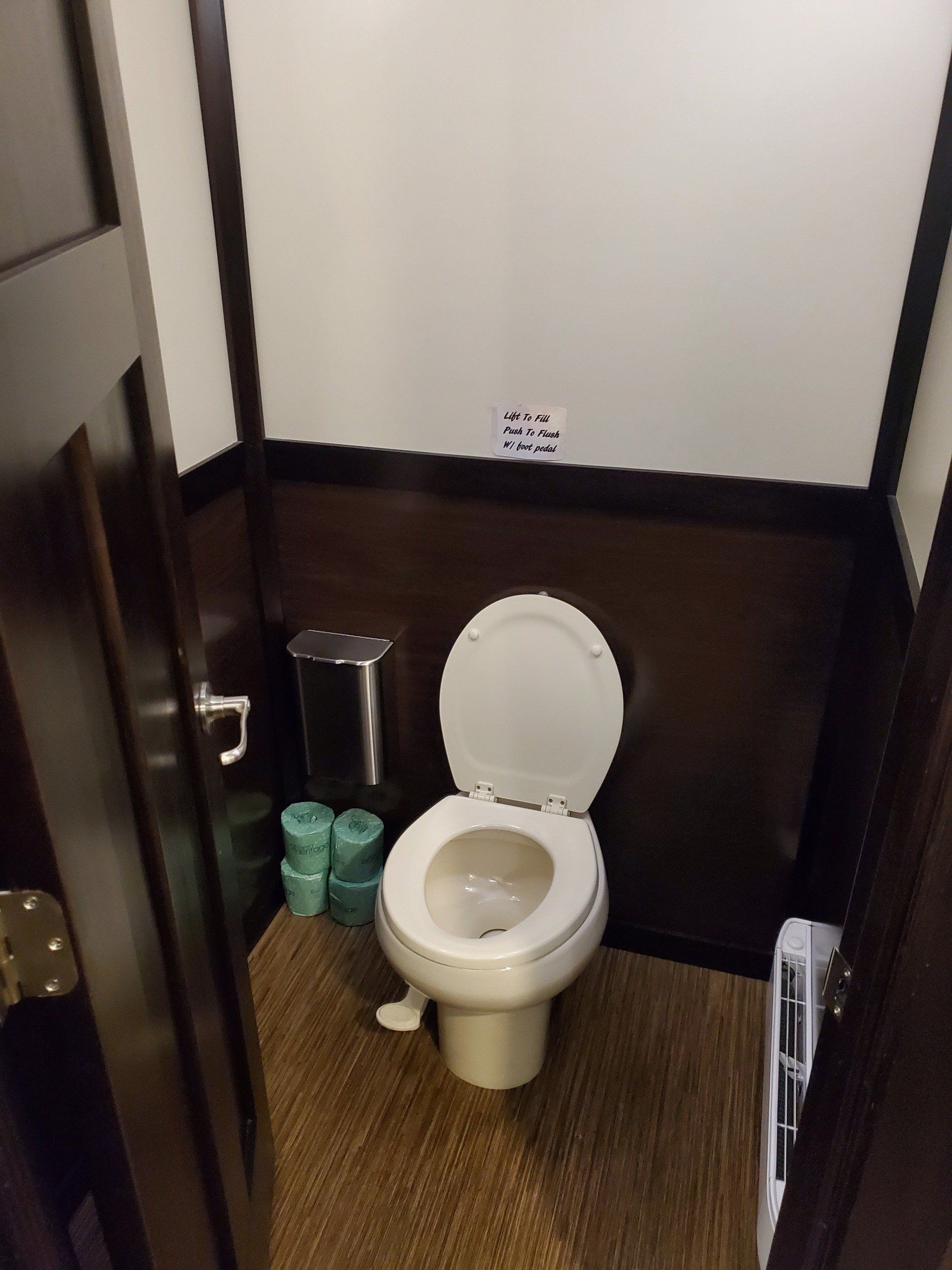 A bathroom with a toilet and a trash can