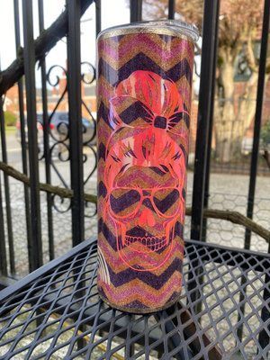 Glittery skull tumbler with red and purple chevron pattern, set outdoors on a metal table.