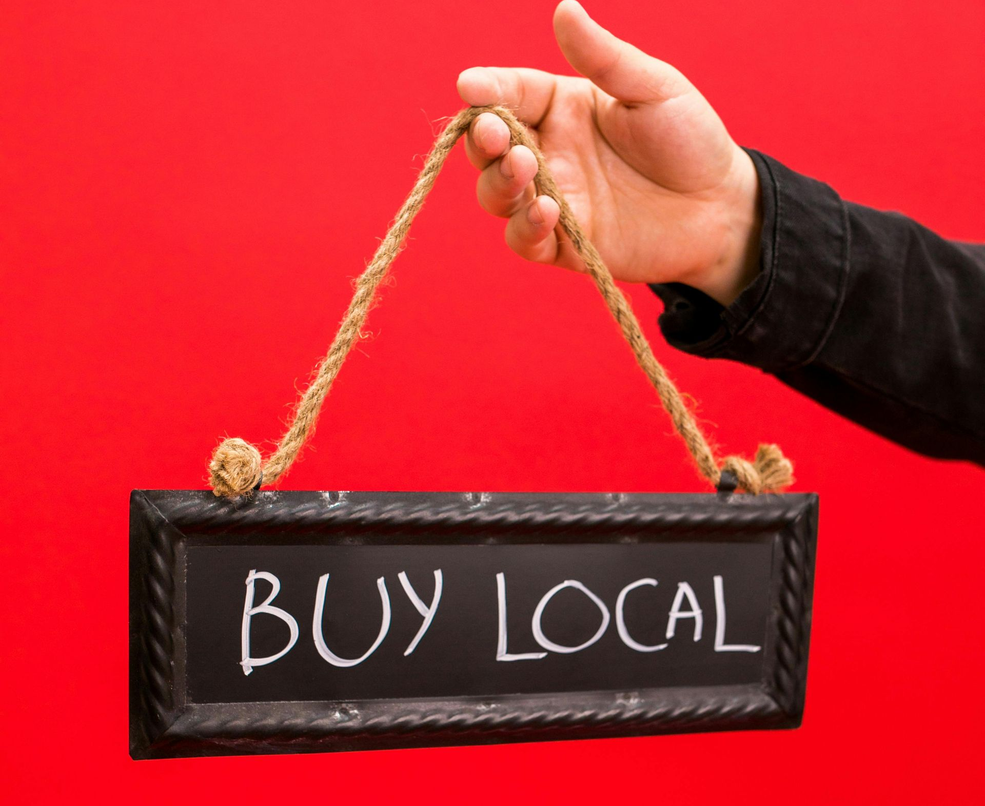 SEO Lakeland, in a black sign with a man holding it by it`s rope hanger, it says in  all caps white letters 