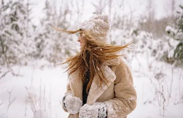 A woman in a fur coat and hat is standing in the snow.