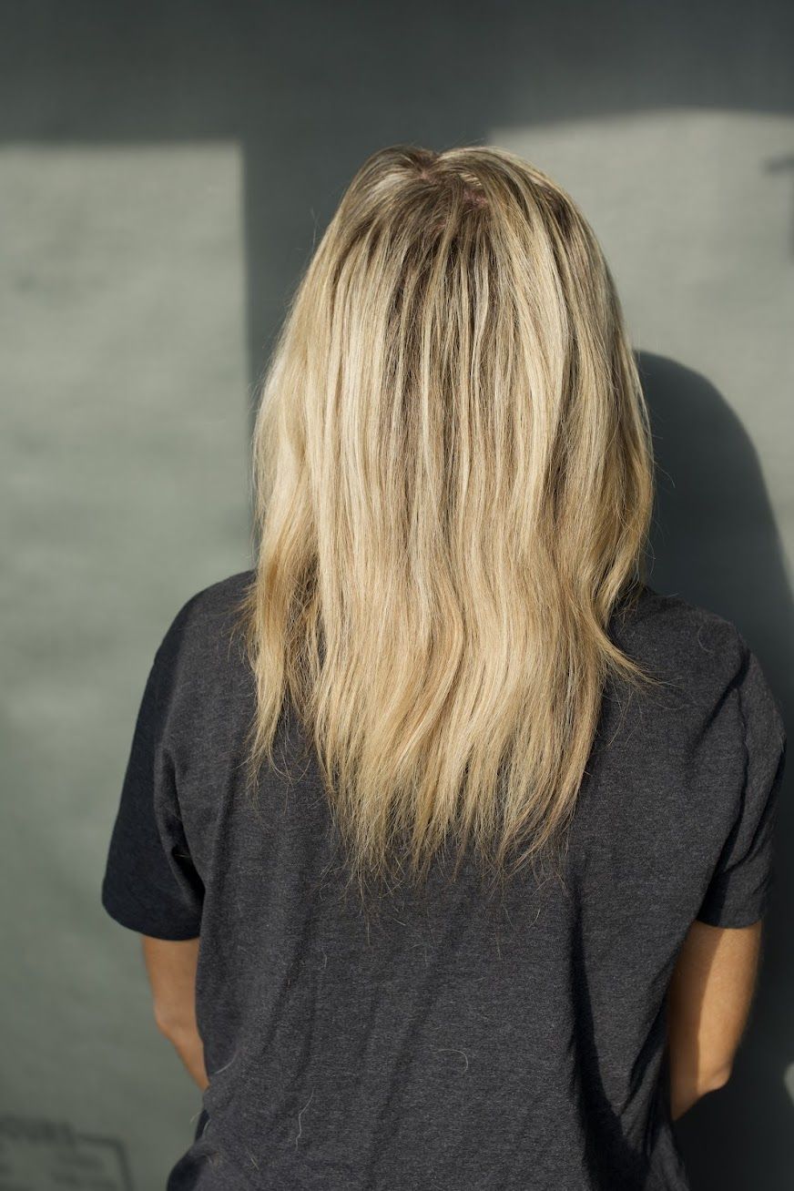 A woman with blonde hair is standing in front of a wall.