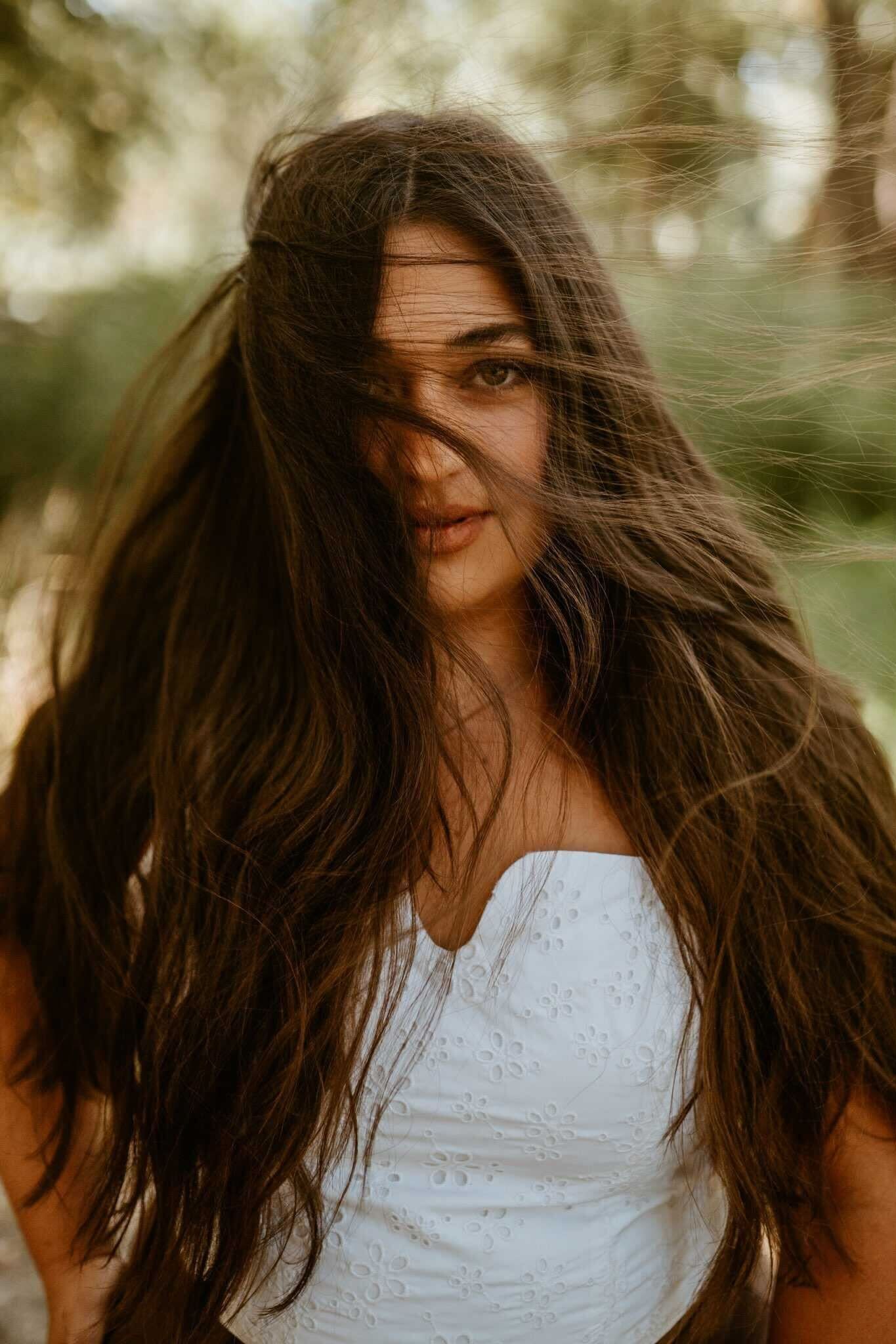 A woman with long hair is wearing a white dress.