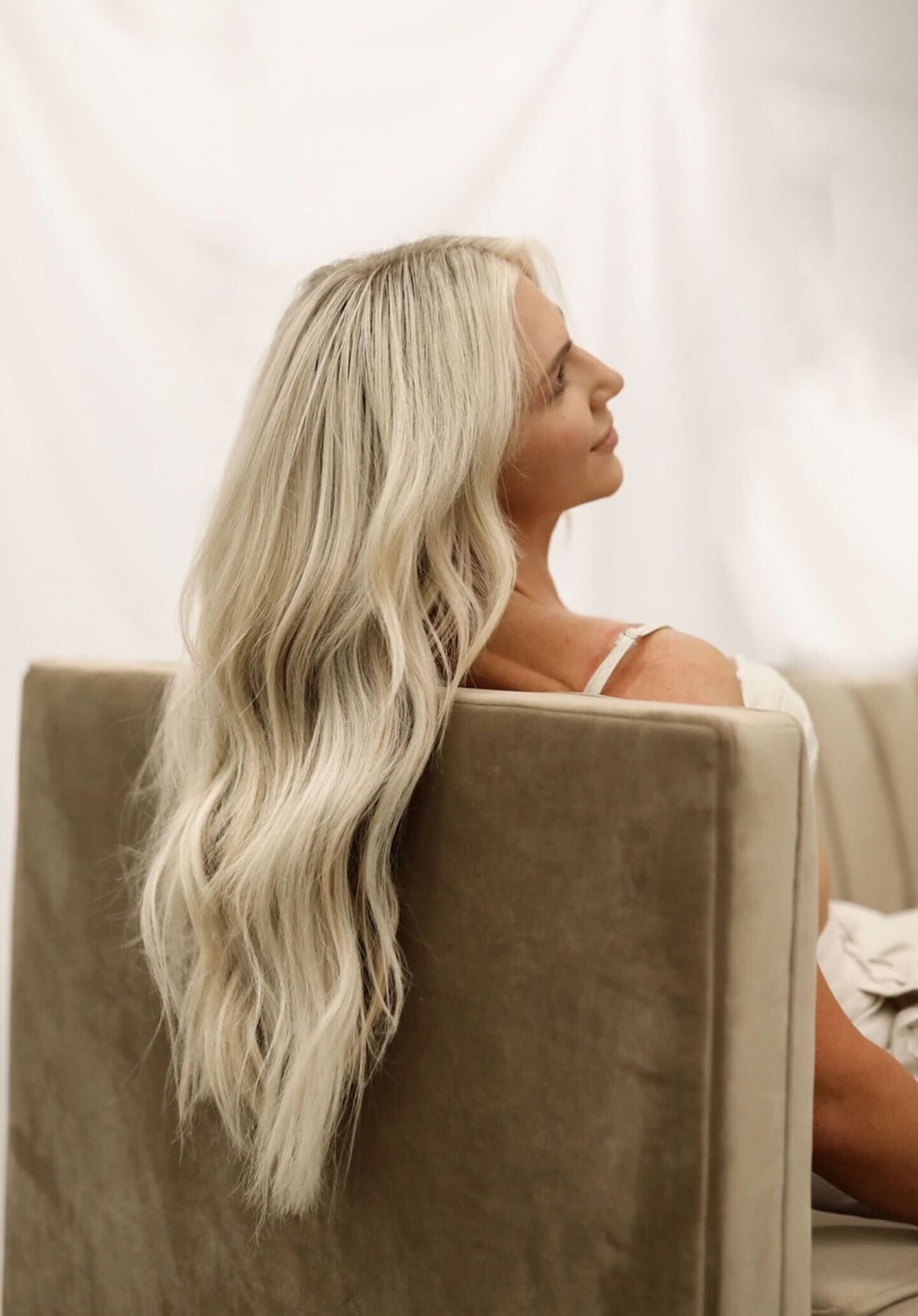 A woman with long blonde hair is sitting on a couch.