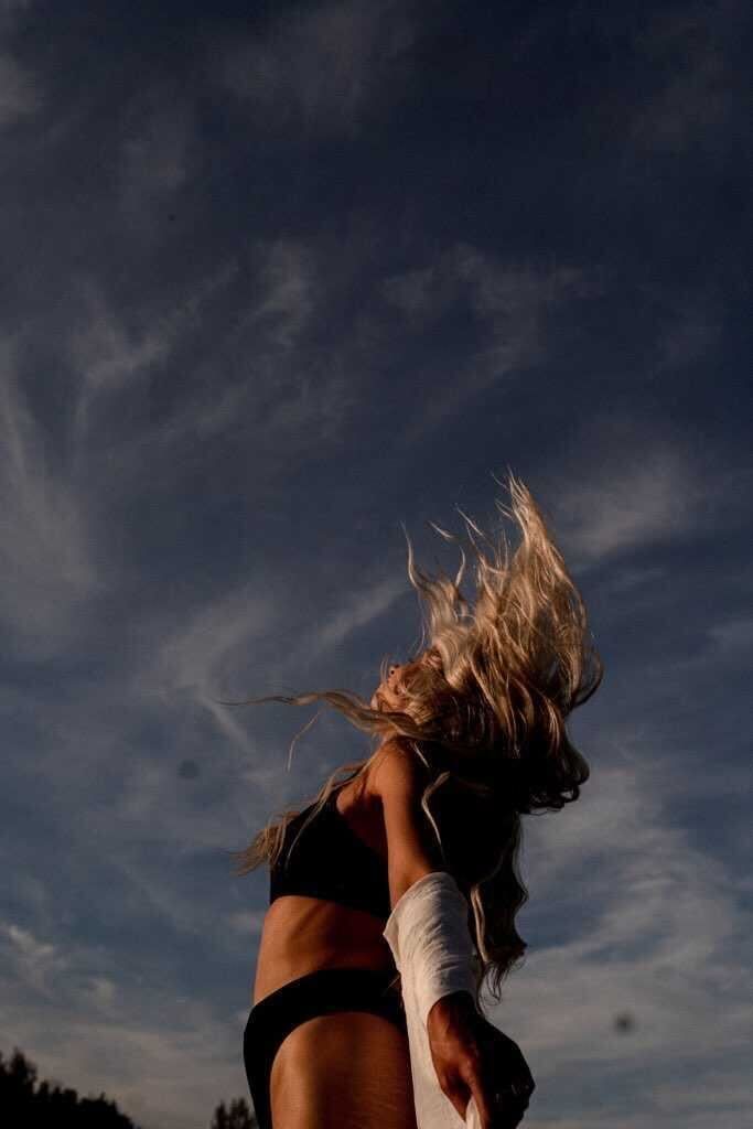 A woman with her hair blowing in the wind covering her face.