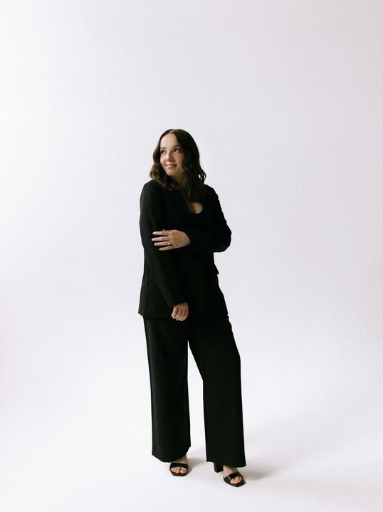 A woman with long hair is sitting on the floor and smiling.