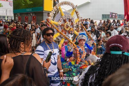 A man is holding a microphone in front of a crowd of people at a carnival.