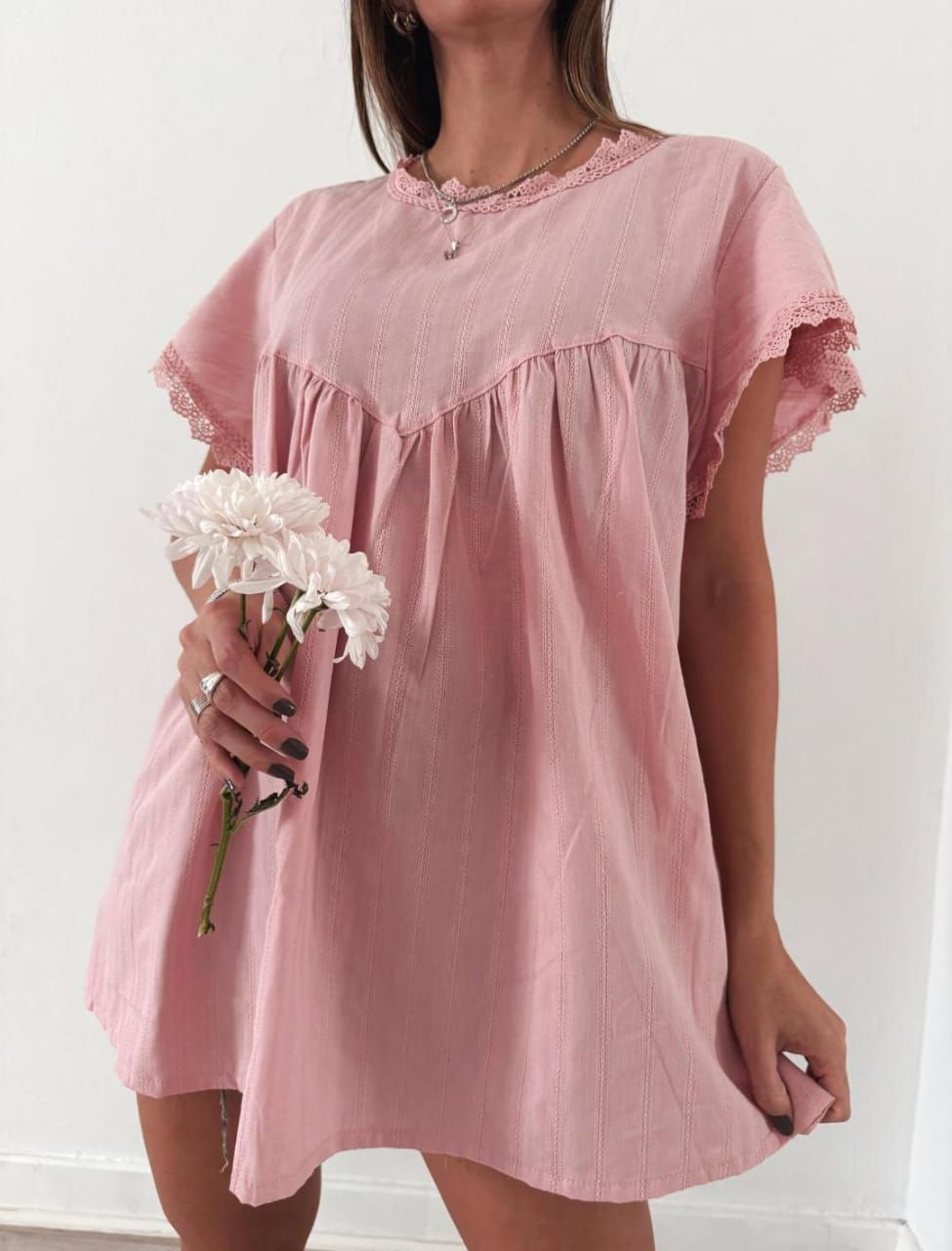 Mujer con vestido rosa sosteniendo flores.