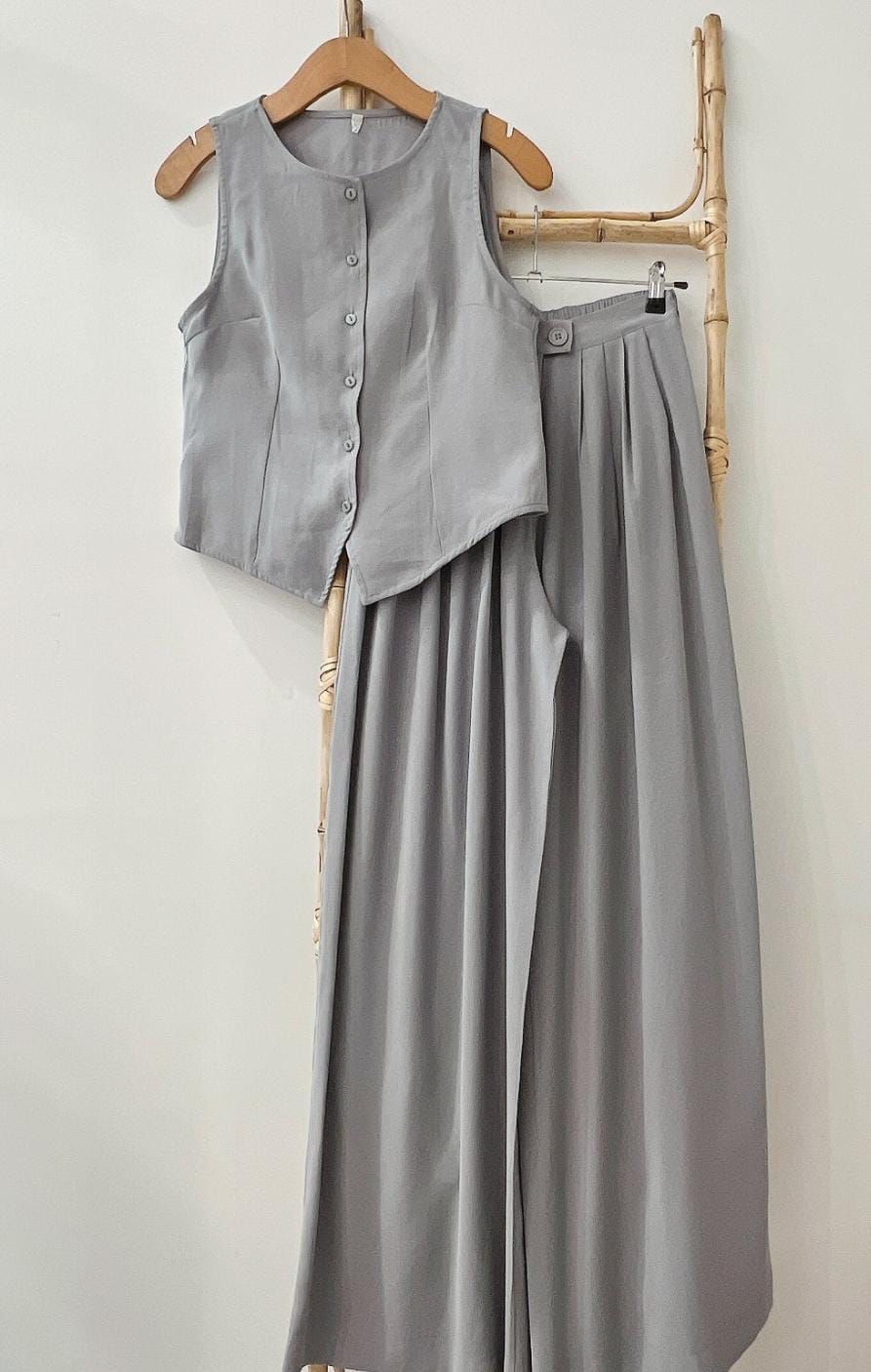 Pila de cinco chalecos abotonados en diferentes colores: beige, gris, negro, blanco y azul marino.