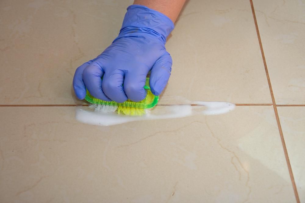 A Person Is Cleaning a Tile Floor — Professional Cleaning Company in Maryborough, QLD