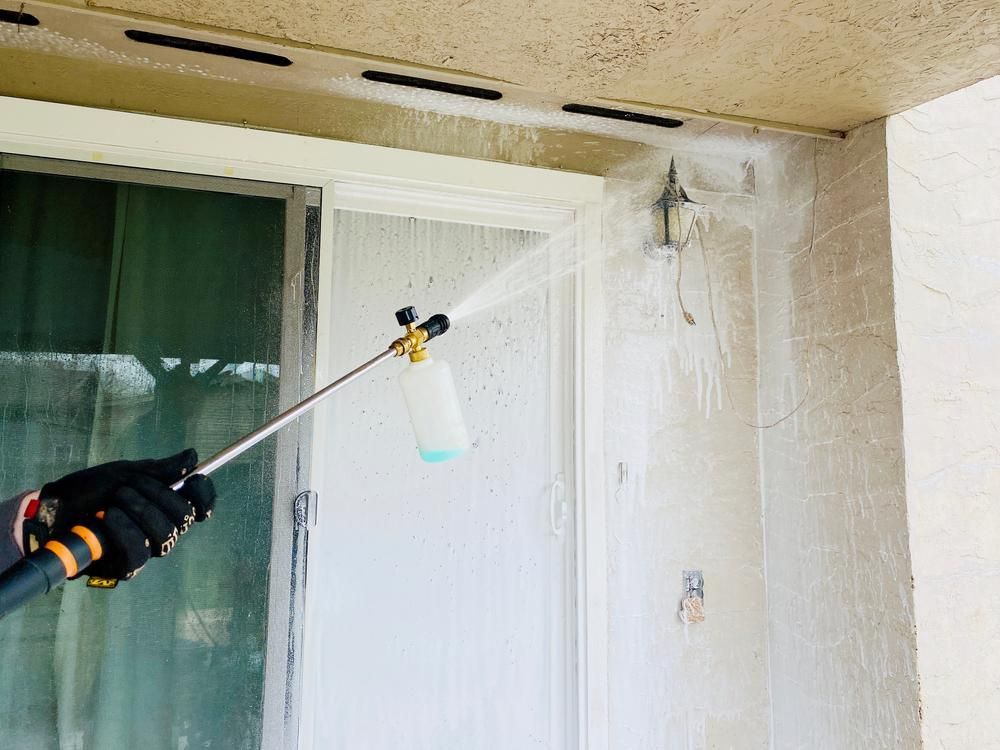 A Person Is Spraying a Wall with A Sprayer — Professional Cleaning Company in Burrum Heads, QLD