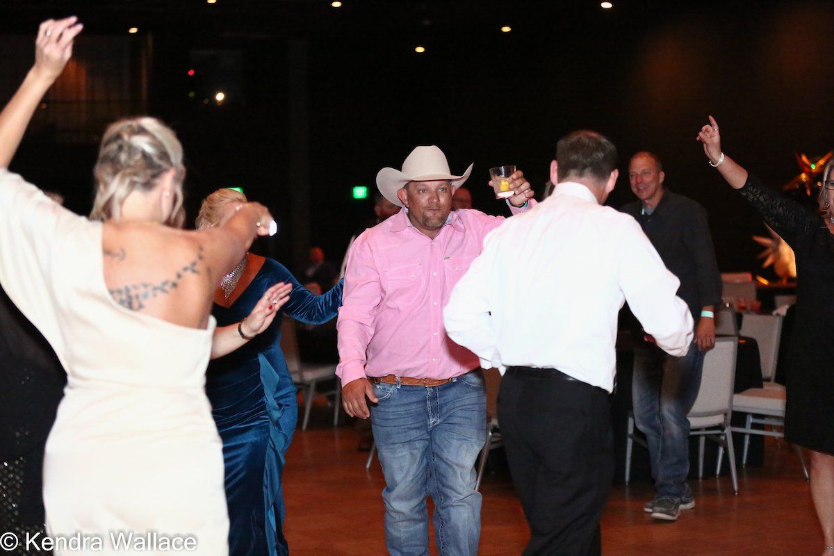 People dancing at a party; man in cowboy hat raises a drink.