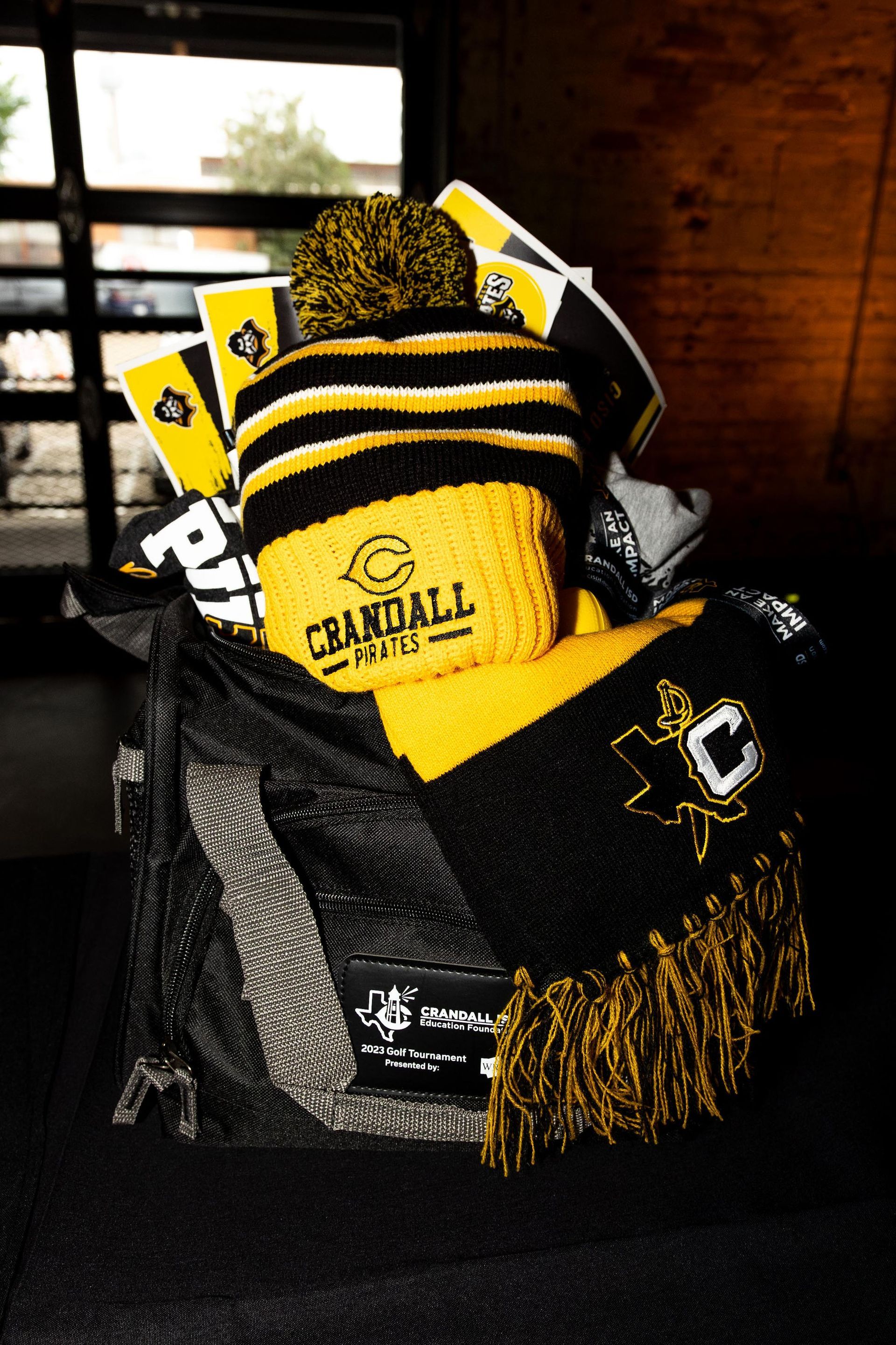 Black and gold Crandall High School gift basket with hat, scarf, and other gear.