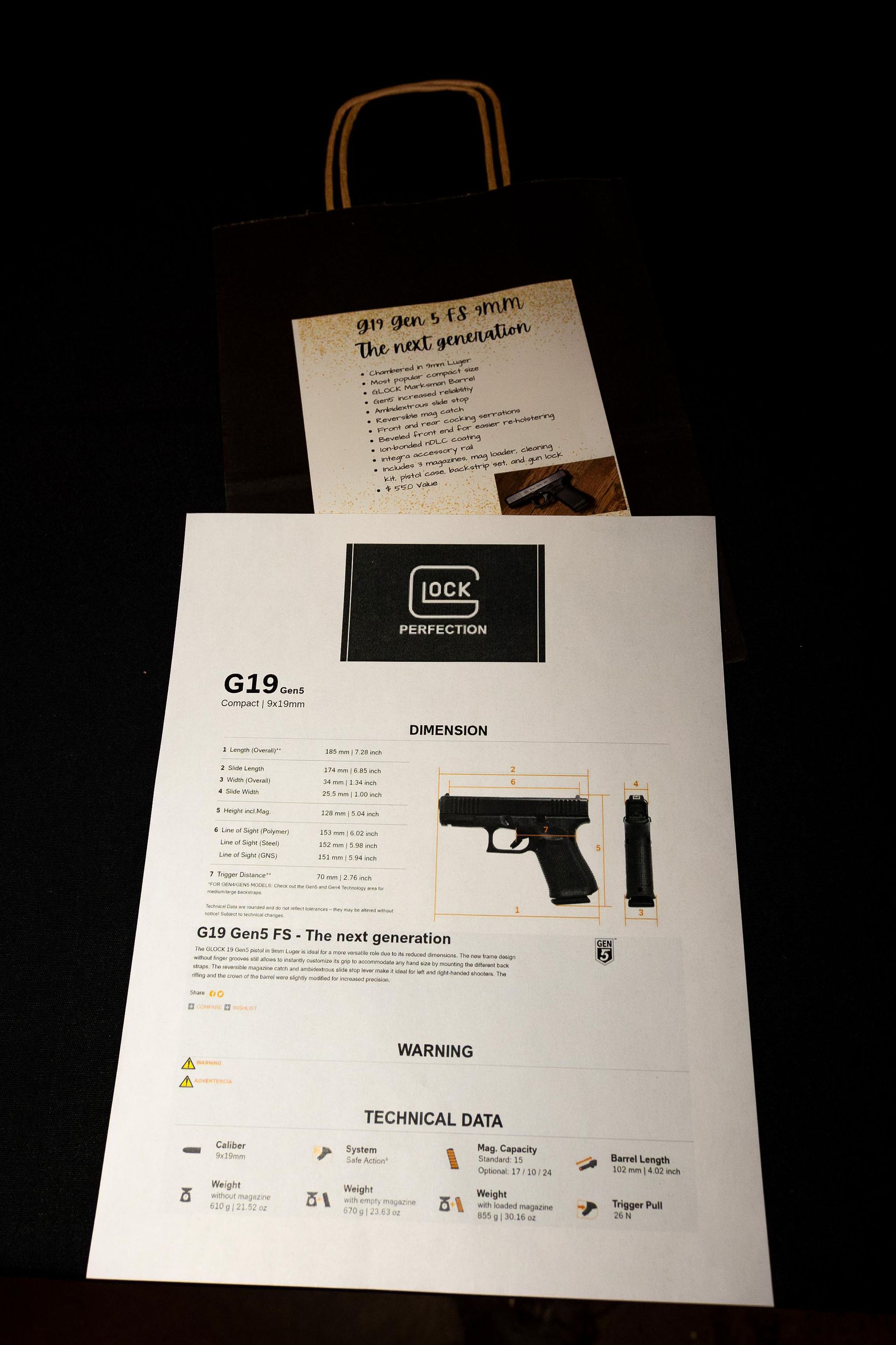 Glock G19 firearm advertisement and a paper bag with notes on a dark background.