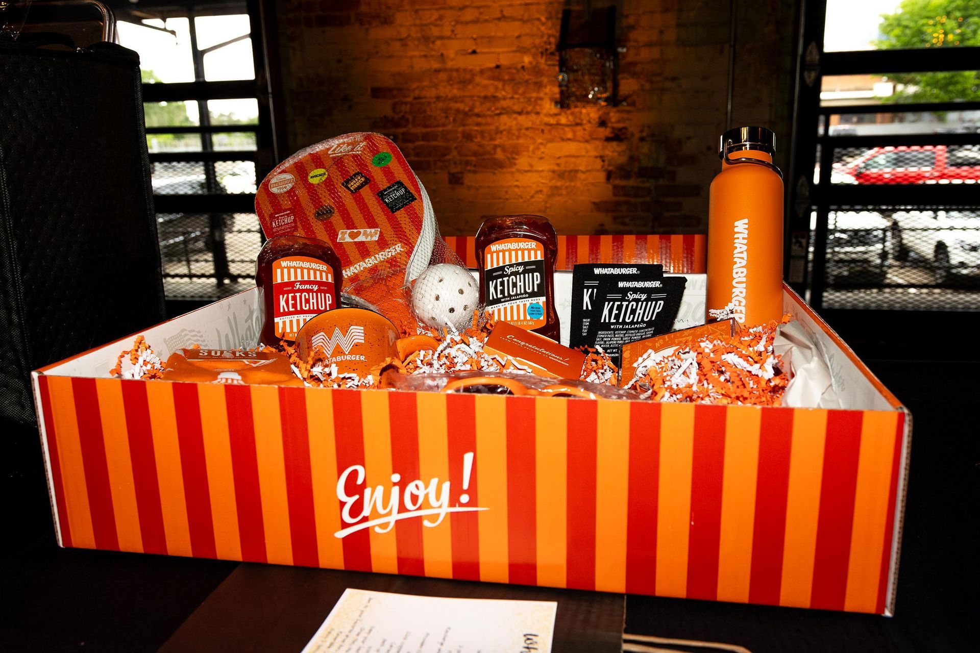 Orange and red gift basket with snacks and a water bottle, with 