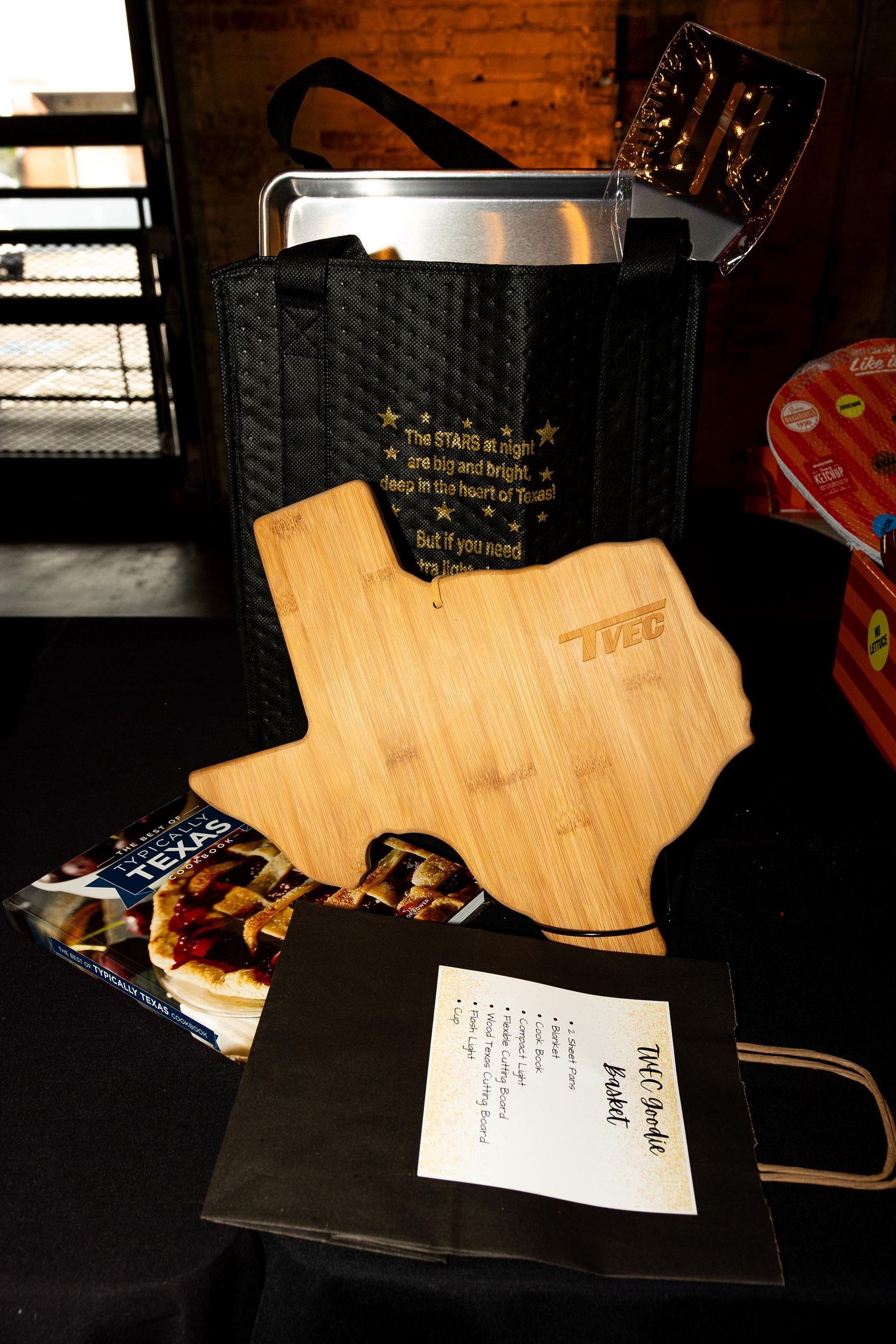 Texas-shaped cutting board, pie, and gift bag with handwritten note on a table.