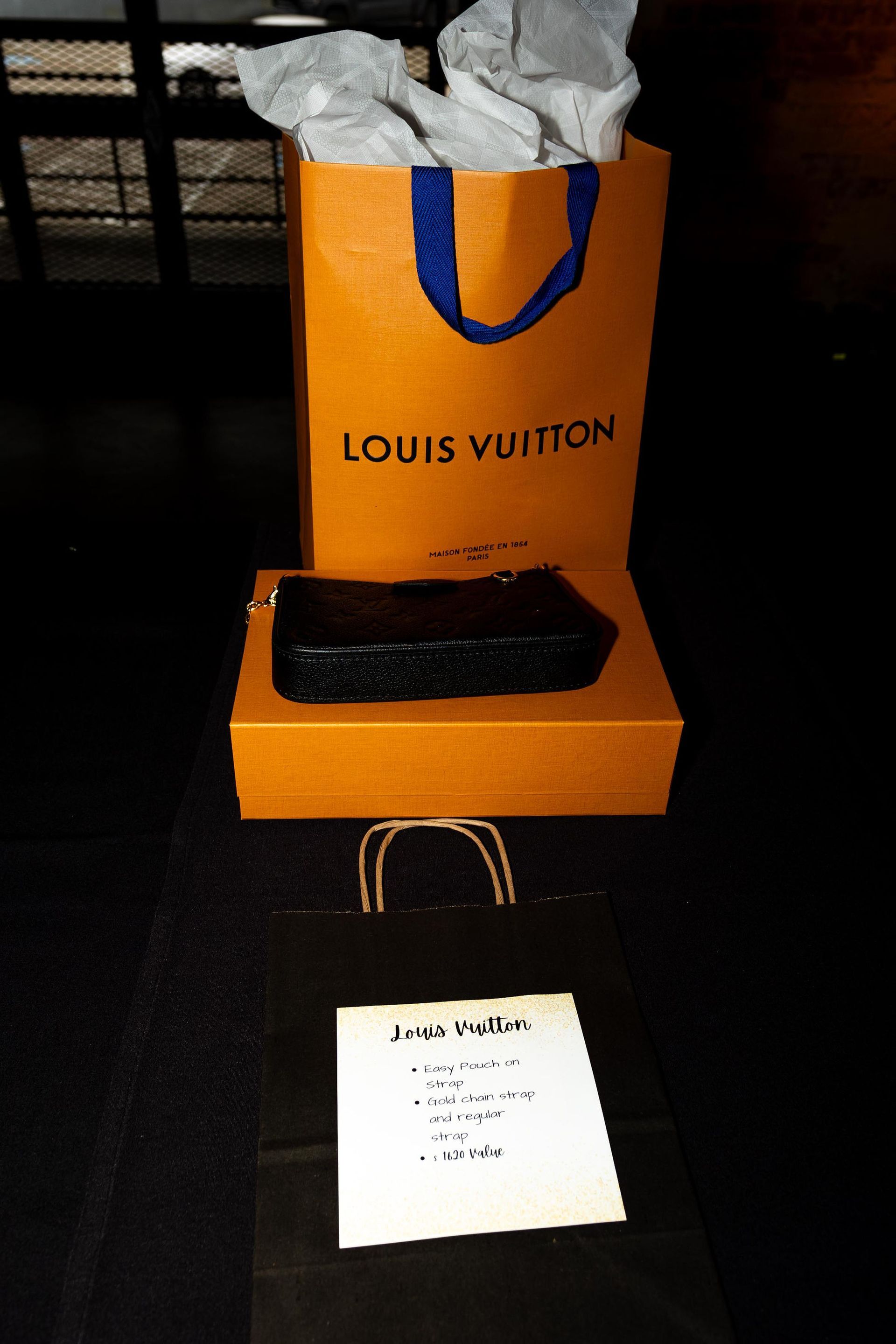 Louis Vuitton shopping bag, box, and receipt on a dark surface.