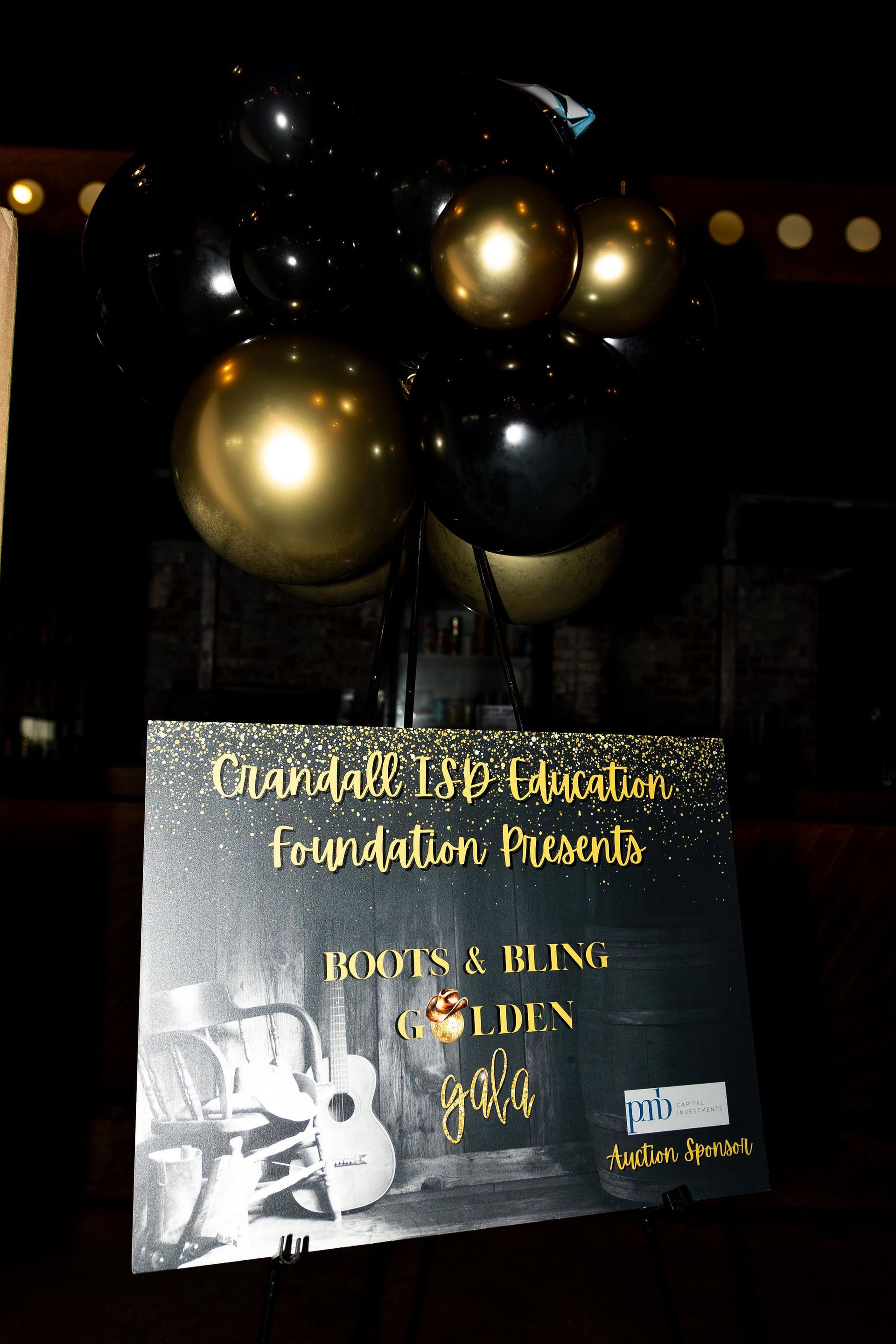 Sign for foundation event with gold and black balloons.
