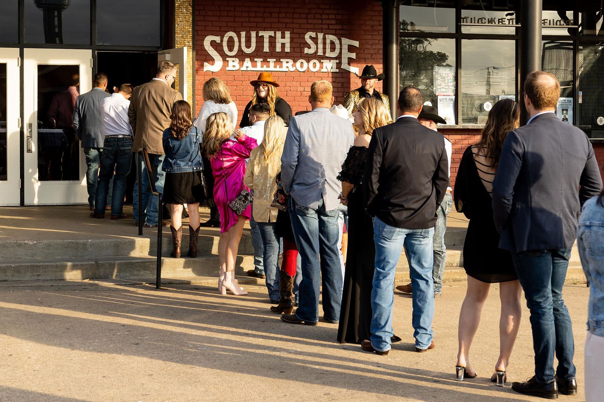 People line up outside the South Side Ballroom, some wearing cowboy hats.