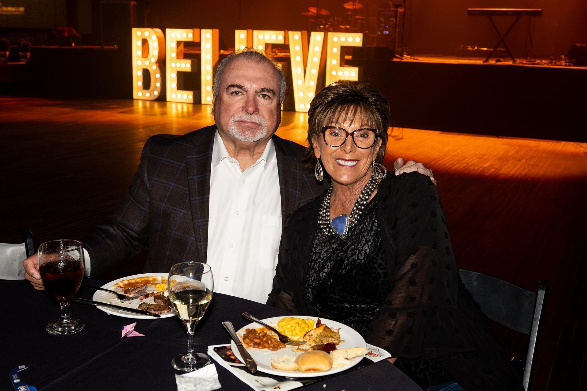 Couple at a table with food and drinks. The word 