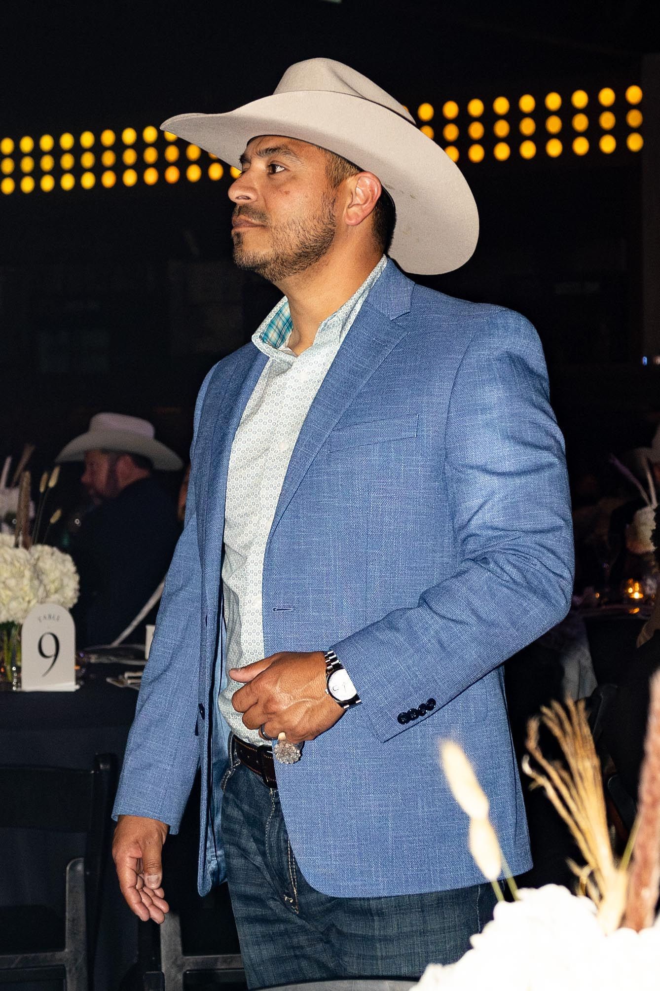 Man in cowboy hat and blue blazer at a formal event.