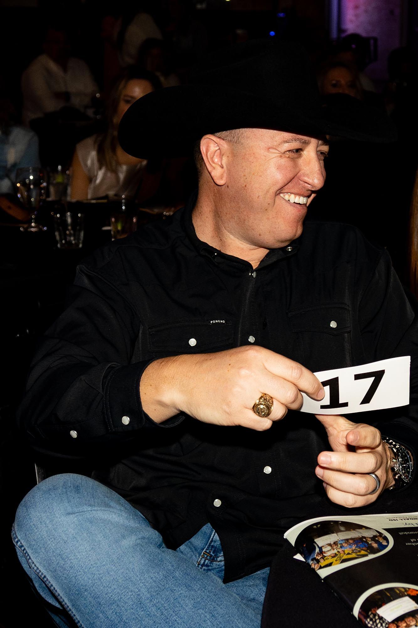 Man in cowboy hat smiles, holding a 