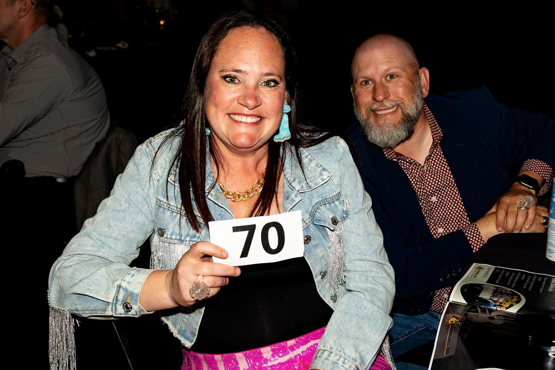 Woman with number 70 smiles with man; event setting, both looking at camera.