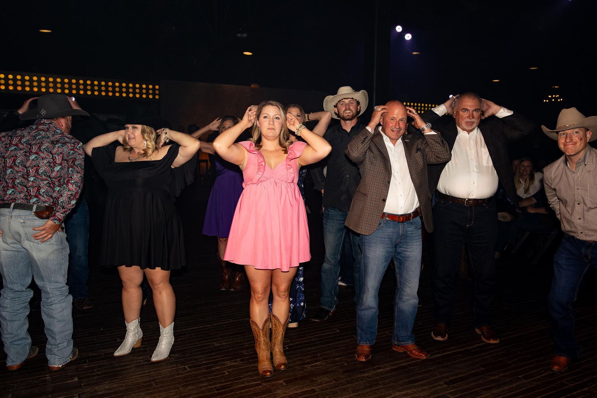 People in cowboy hats dancing, making 