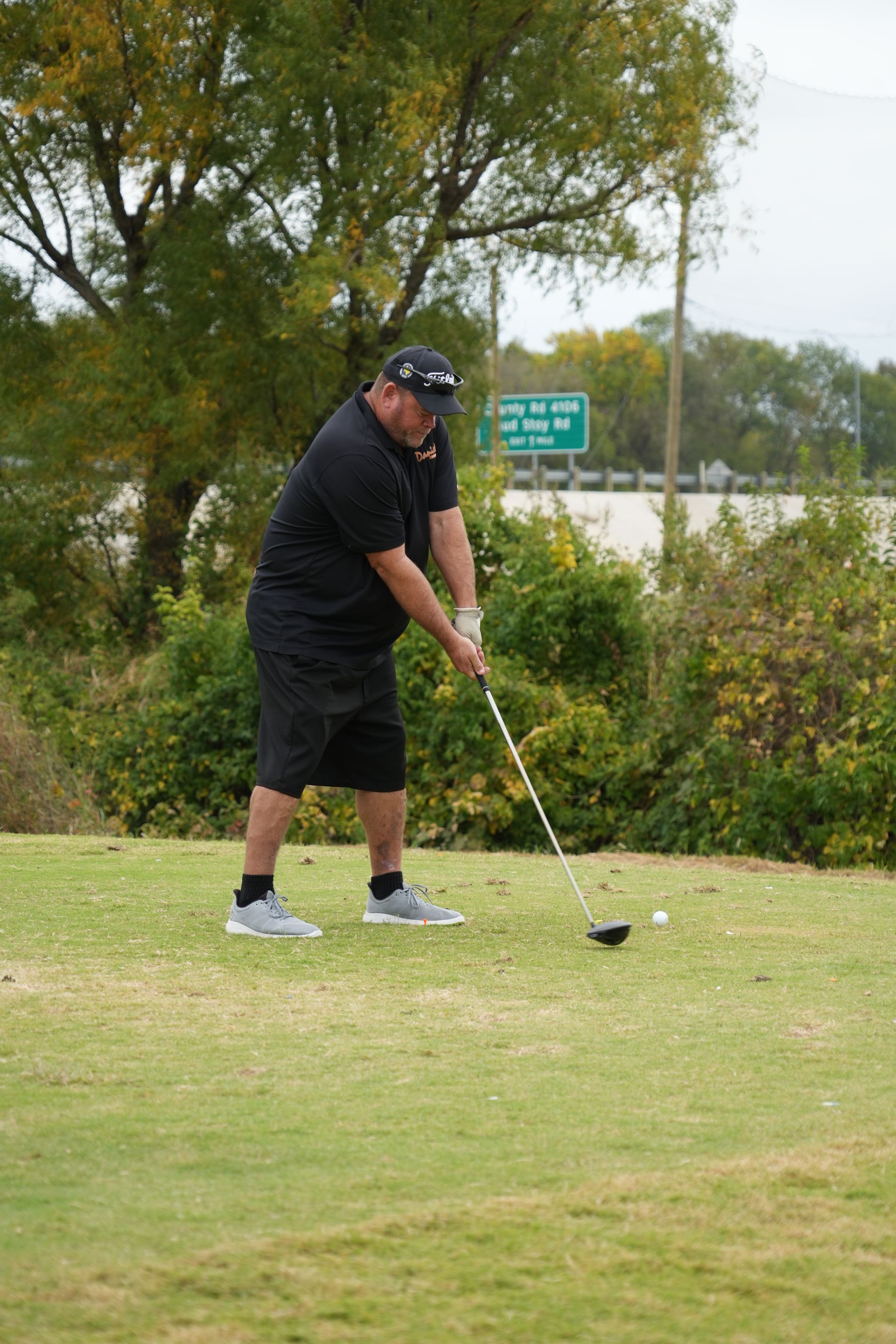 Man in black clothes playing golf on a green course.