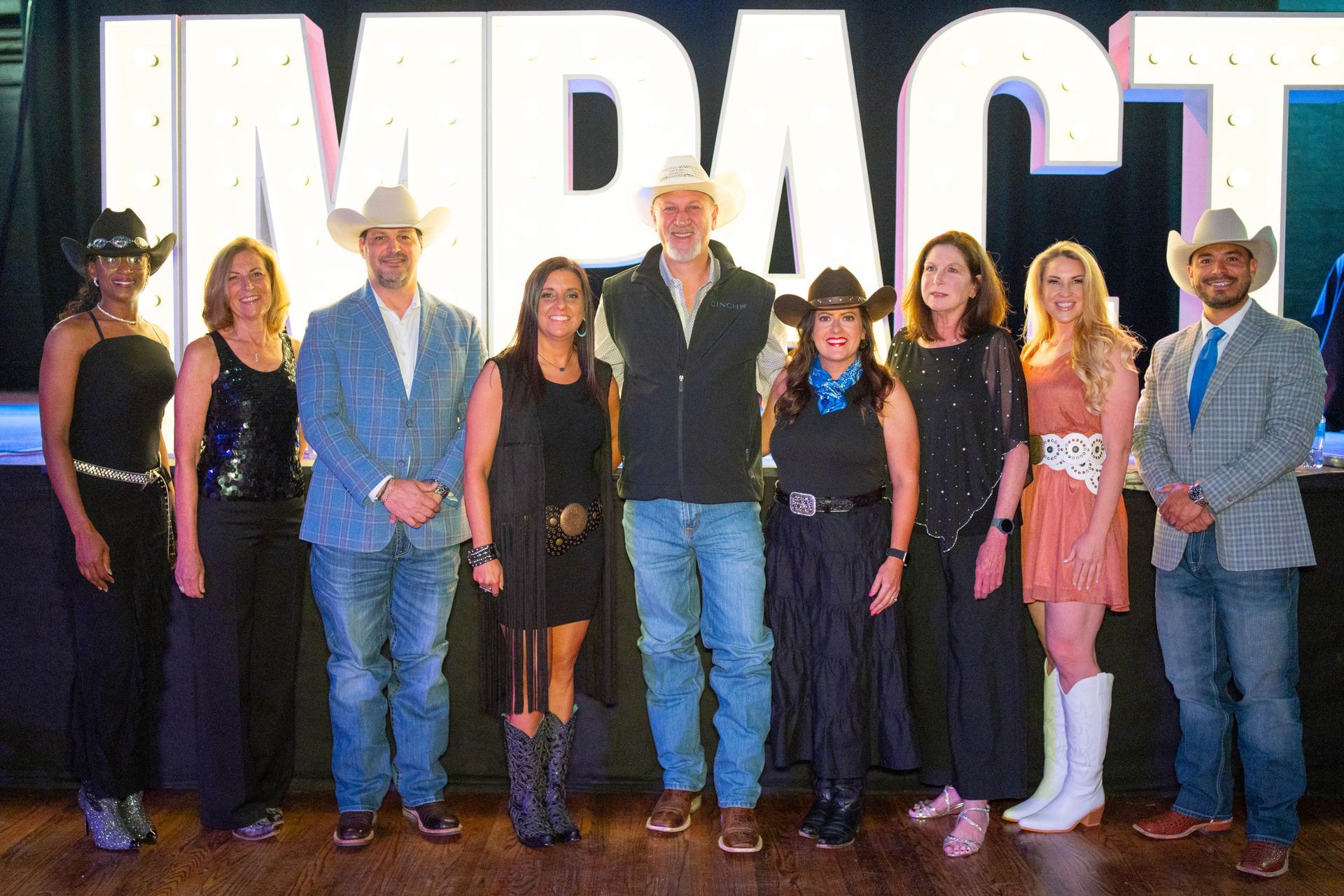 Group of people, some in cowboy hats, posing in front of 