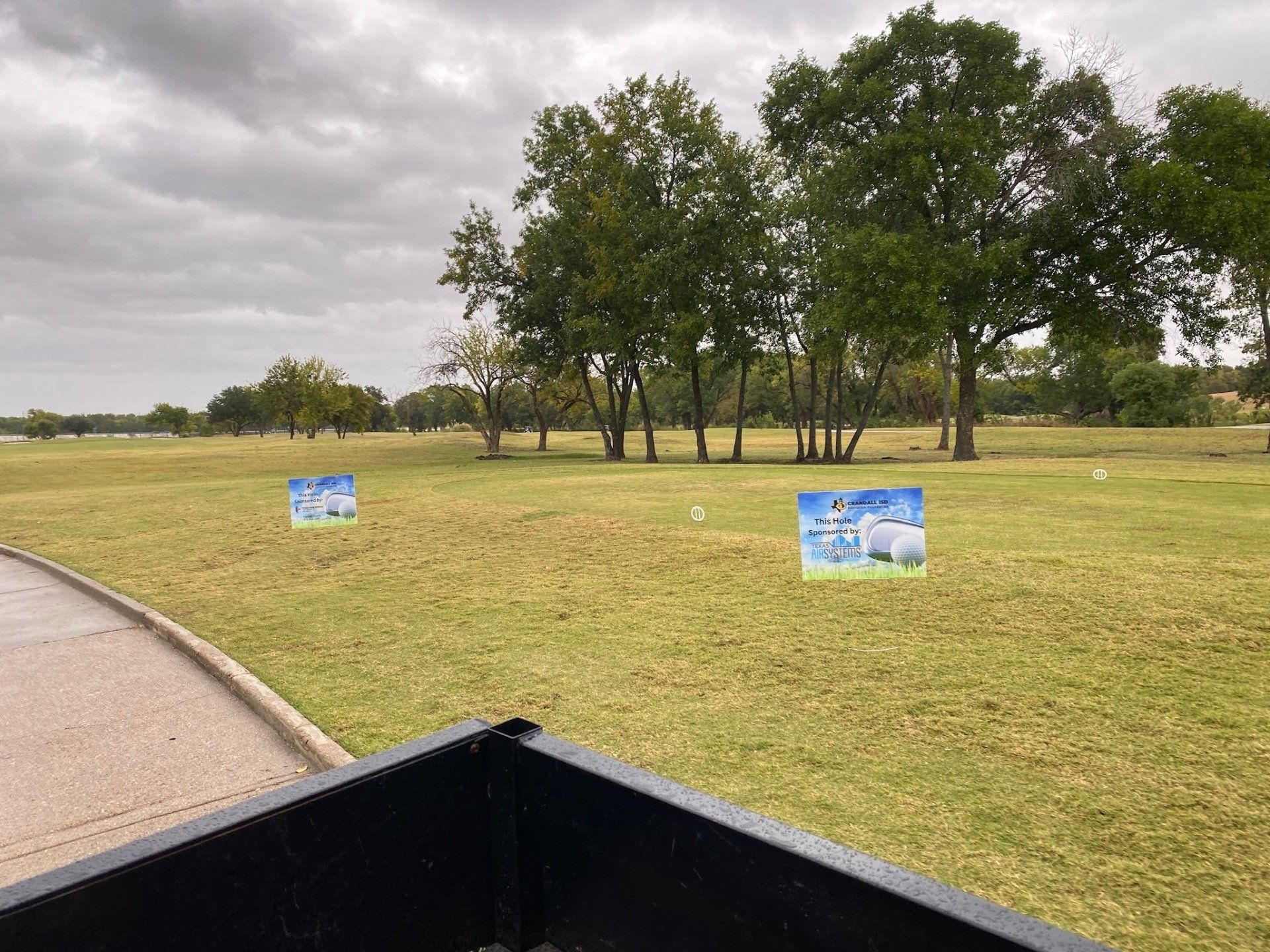 Golf course tee boxes with signs on a cloudy day.