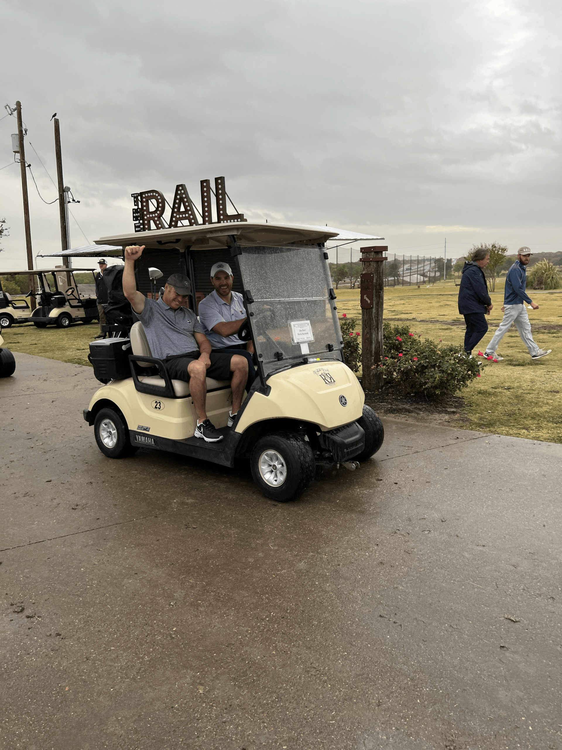Two men in a beige golf cart with 