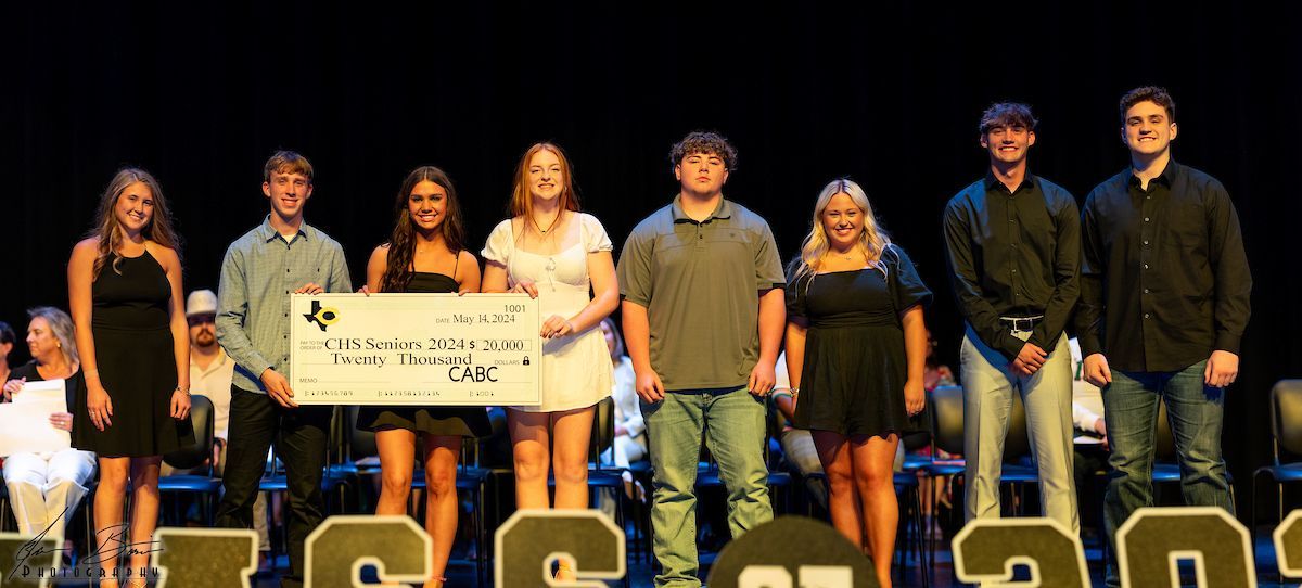 A group of young adults on stage holding a large check, likely for a donation.