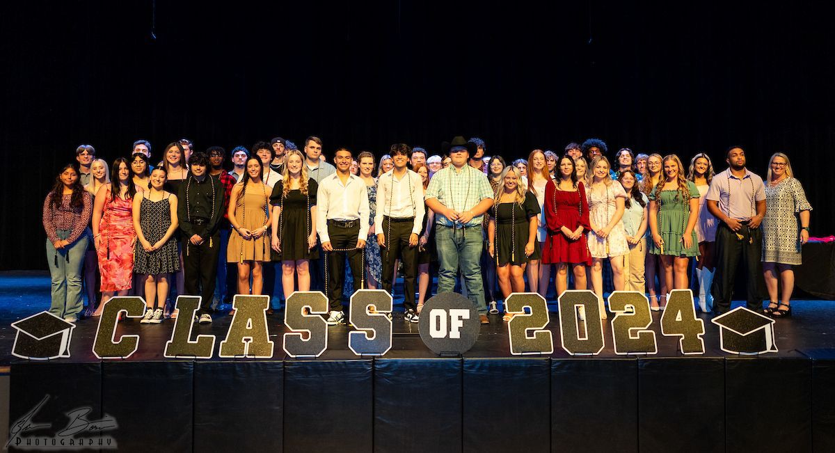 Class of 2024 graduates on stage behind large letters. Students are smiling, posing, and celebrating.