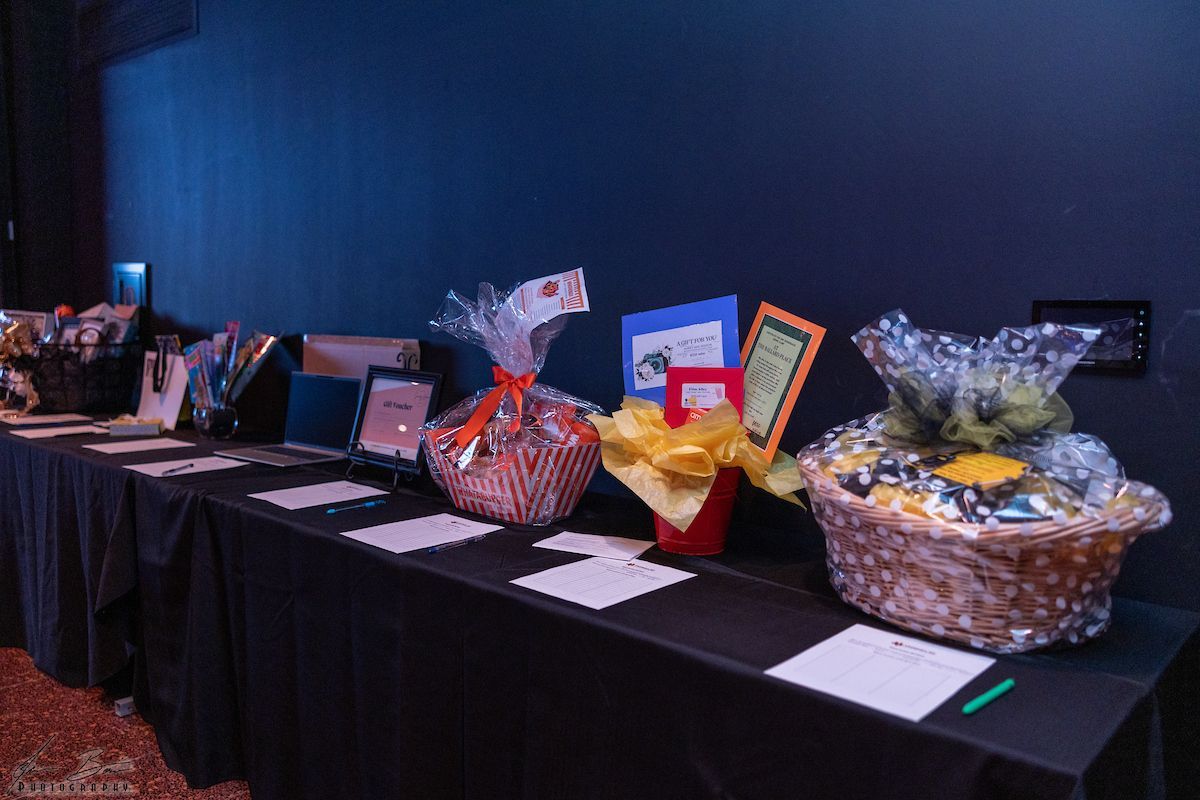 Baskets with items on a table, likely for a silent auction, in a dark room.
