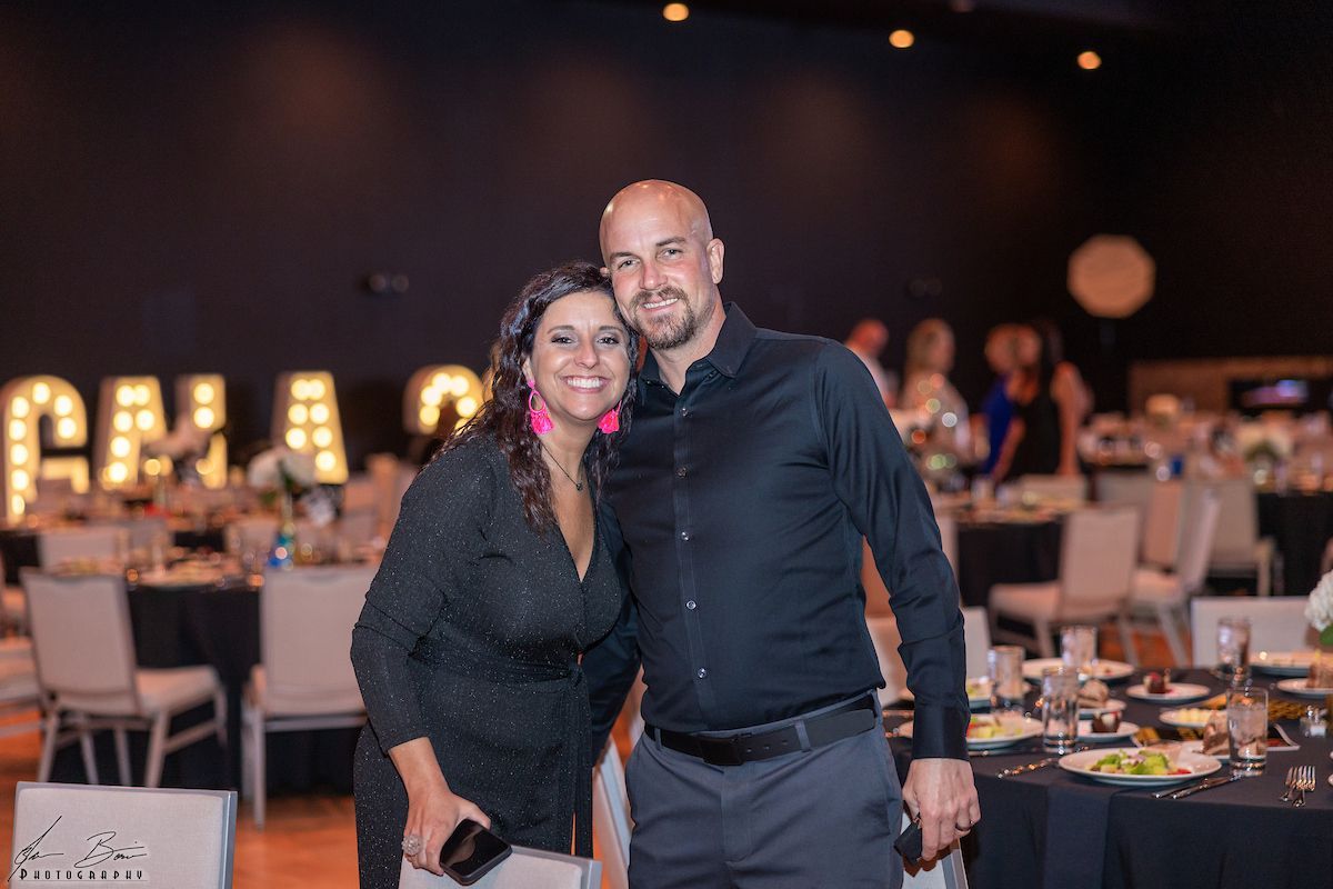 Woman and man smiling, posing together at an event. 