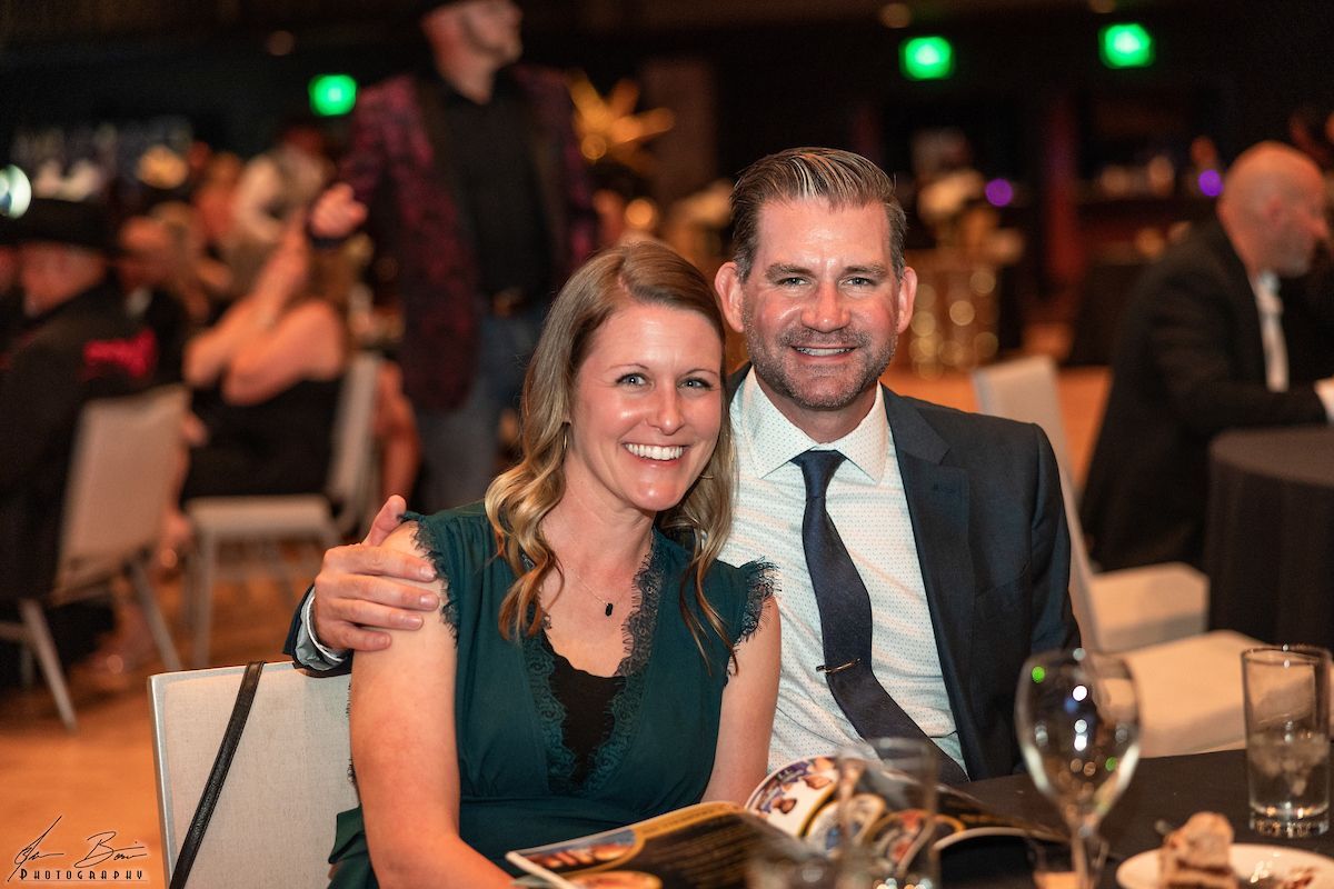 Couple smiling at a formal event, woman in green dress, man in suit.