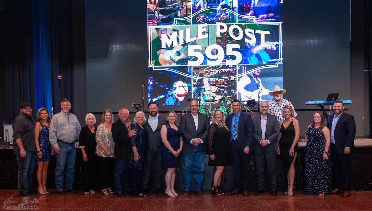 Group of people posing in front of a screen that says 