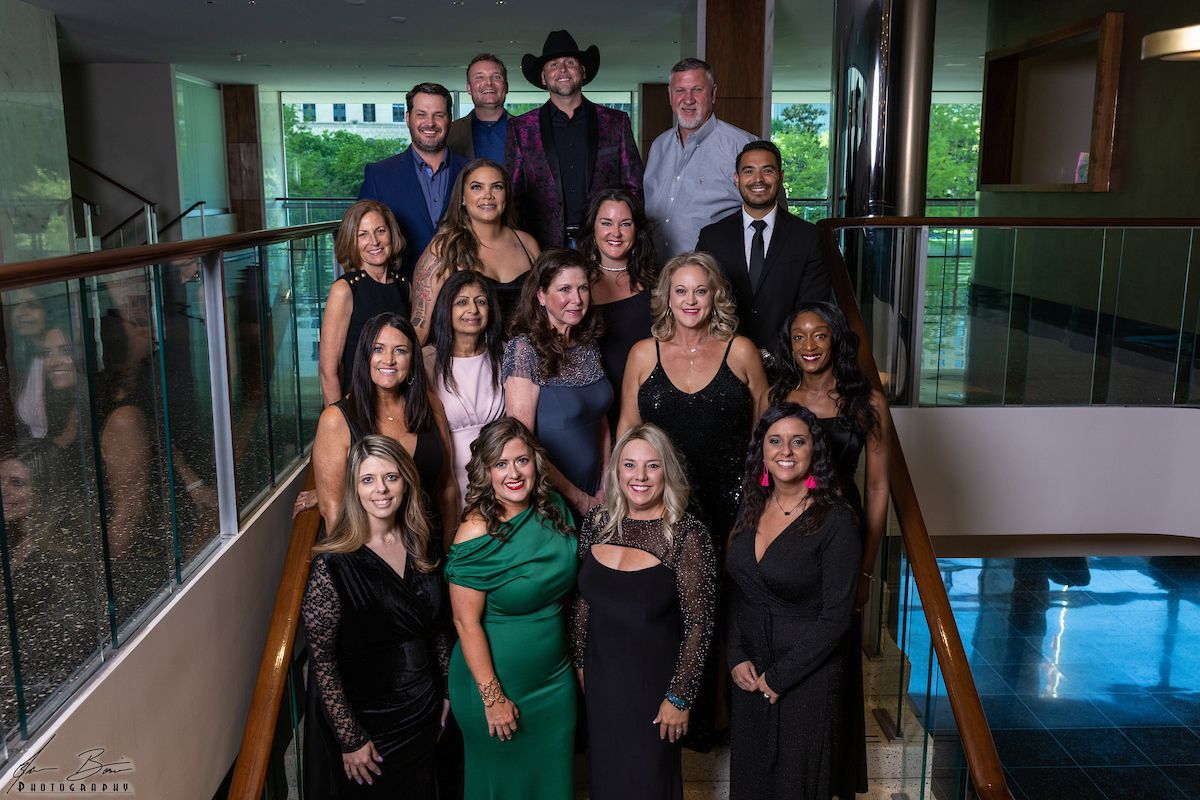 Group of people posing on stairs, various outfits. Well-lit hallway.