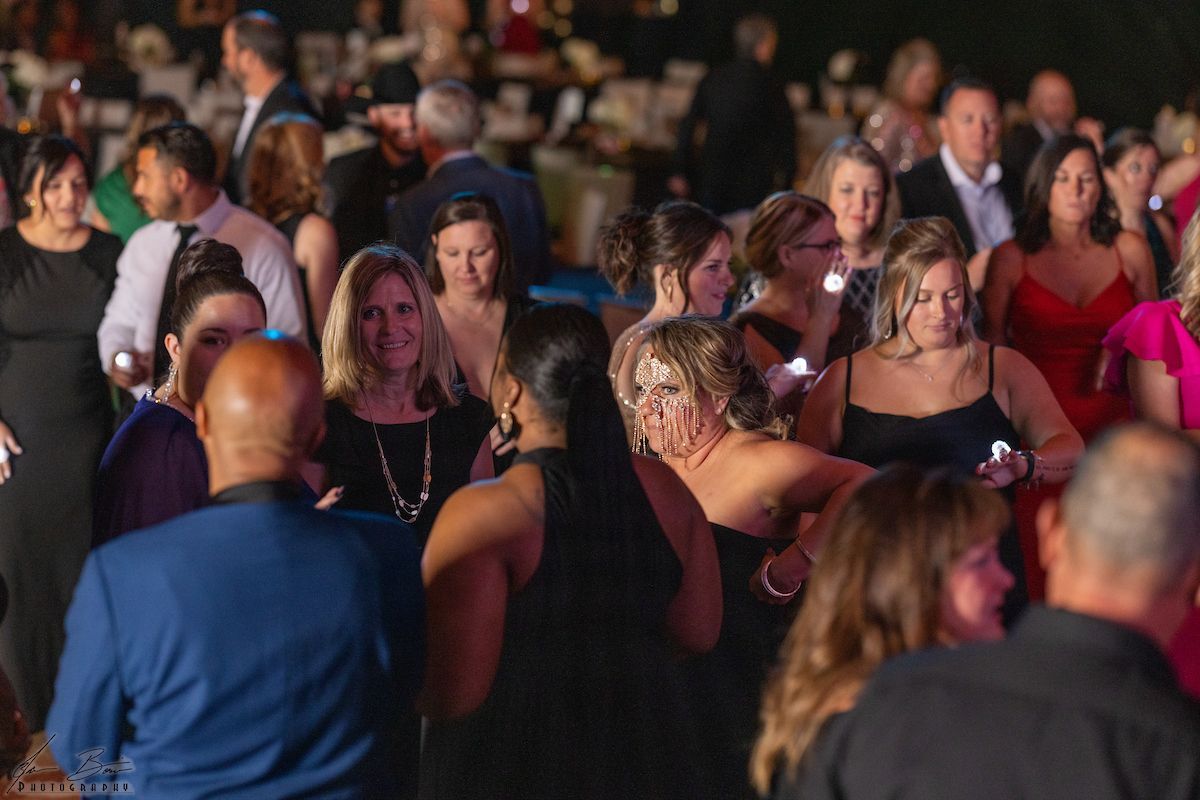 People in formal attire at an evening event, socializing and illuminated by ambient light.